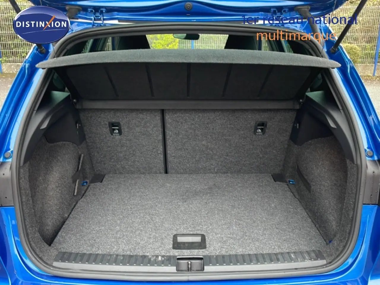 Coffre ouvert vu de l'arrière d'un SEAT Arona bleu saphir métal avec toit blanc, montrant un espace de chargement vide.