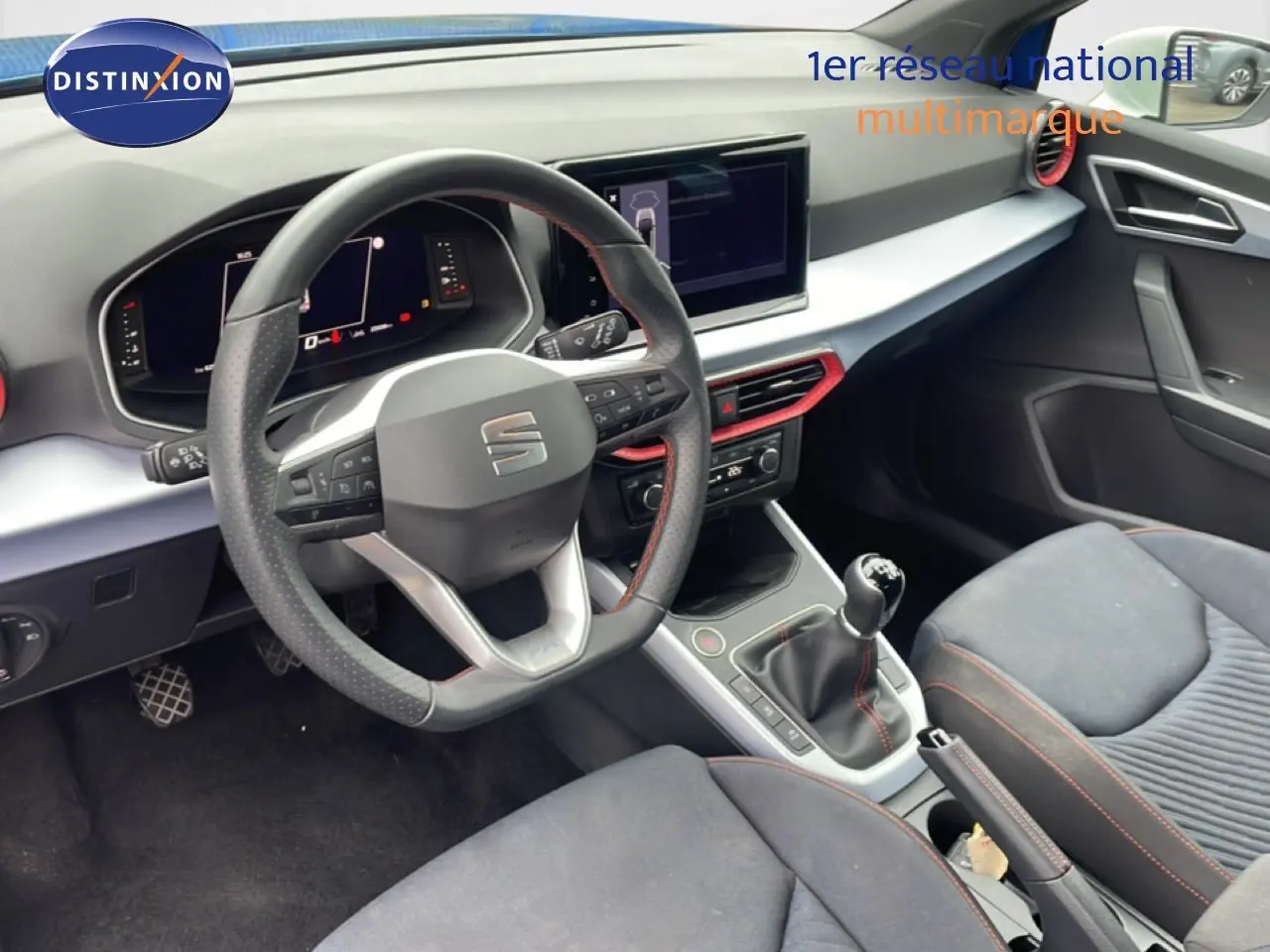 Vue intérieure côté conducteur du tableau de bord et volant de la SEAT Arona 2025 avec finitions rouges et volant cuir.