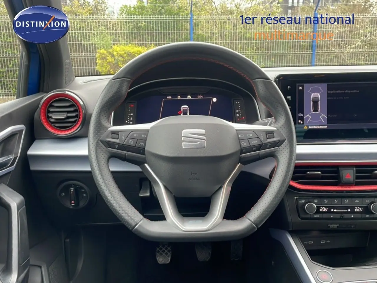 Vue intérieure centrée sur le volant perforé de la SEAT Arona 2025 avec détails rouges et tableau de bord numérique.