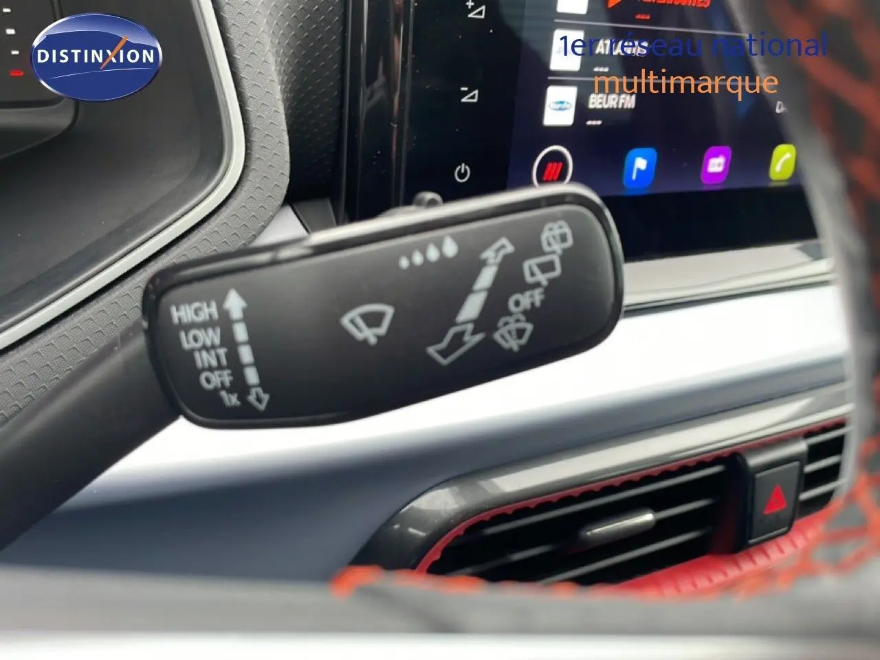 Gros plan sur la commande d’essuie-glace dans l’habitacle du SEAT Arona 2025, volant cuir rouge partiellement visible.