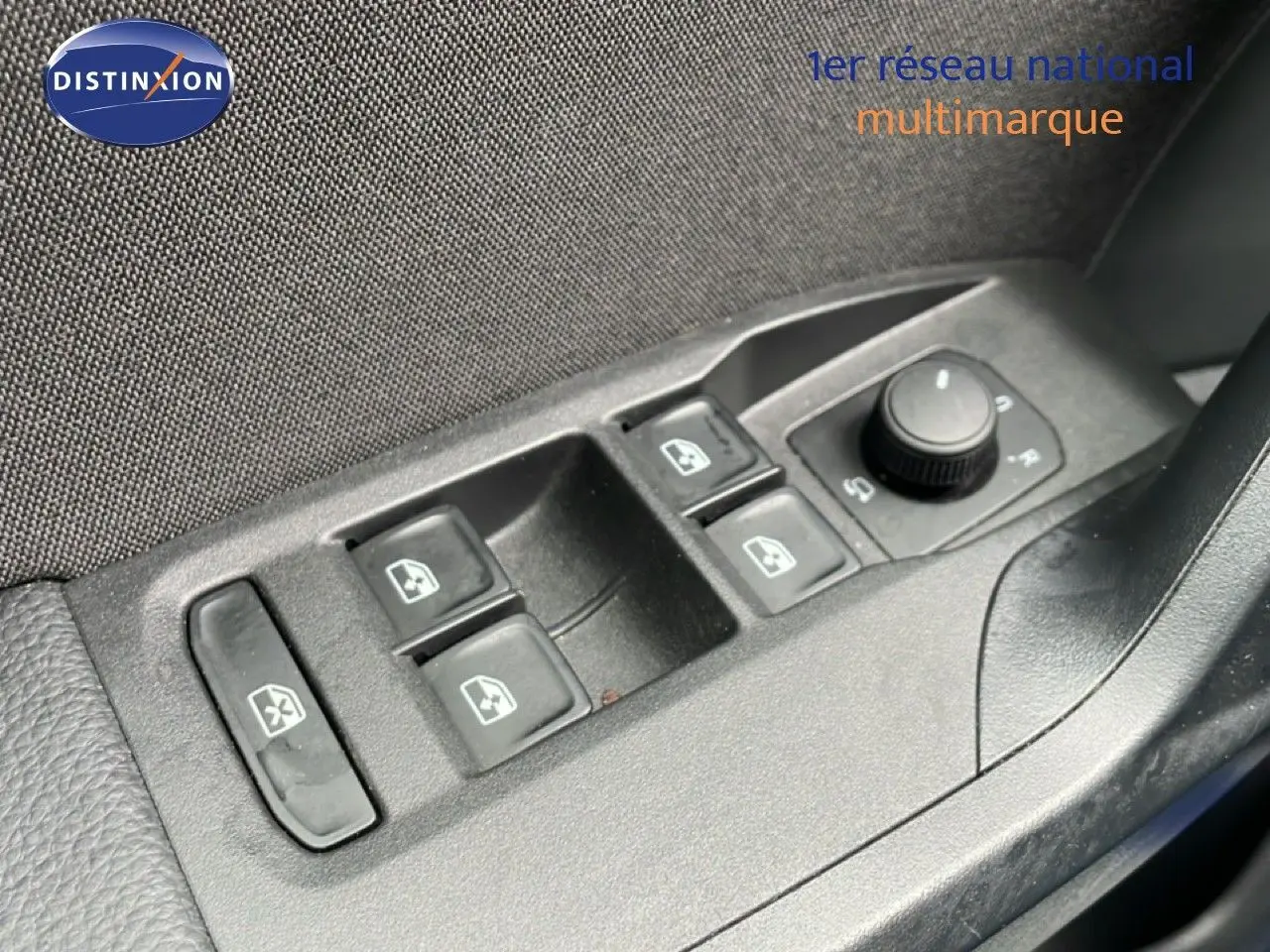 Gros plan sur les commandes des vitres électriques et rétroviseurs côté conducteur du SEAT Arona bleu saphir 2025.