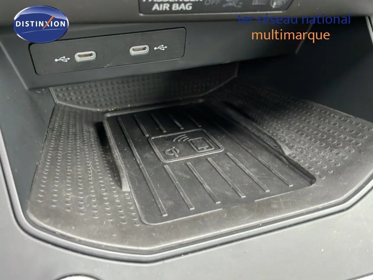 Gros plan sur la zone de recharge sans fil et ports USB dans l'habitacle du SEAT Arona bleu saphir toit blanc.