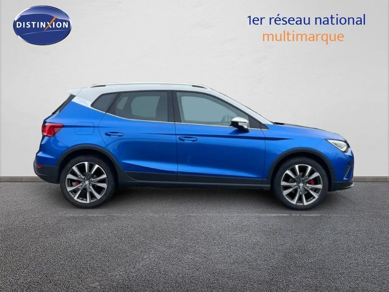 Vue de profil côté gauche d'un SEAT Arona 2025 bleu saphir métallisé avec toit blanc et jantes alliage noires.