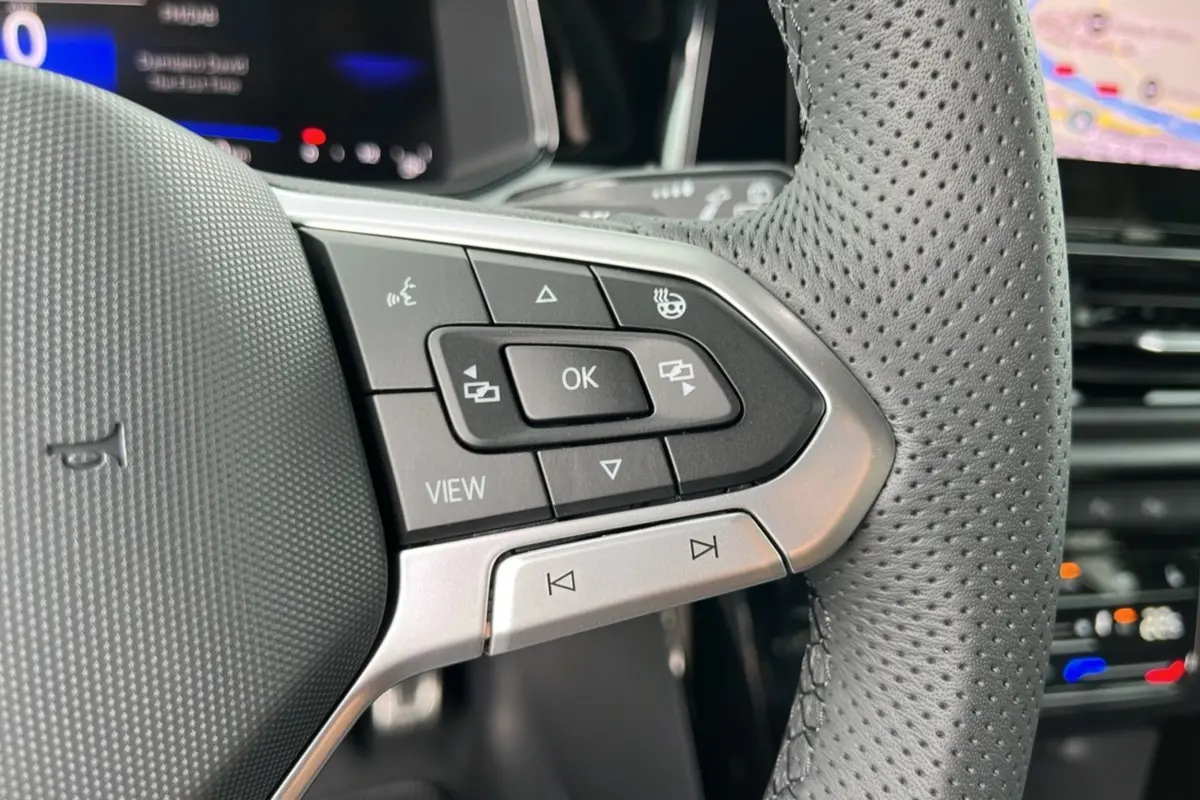 Gros plan sur le volant cuir perforé du Volkswagen T-Roc TDI 150 R-Line Black avec commandes multifonctions.