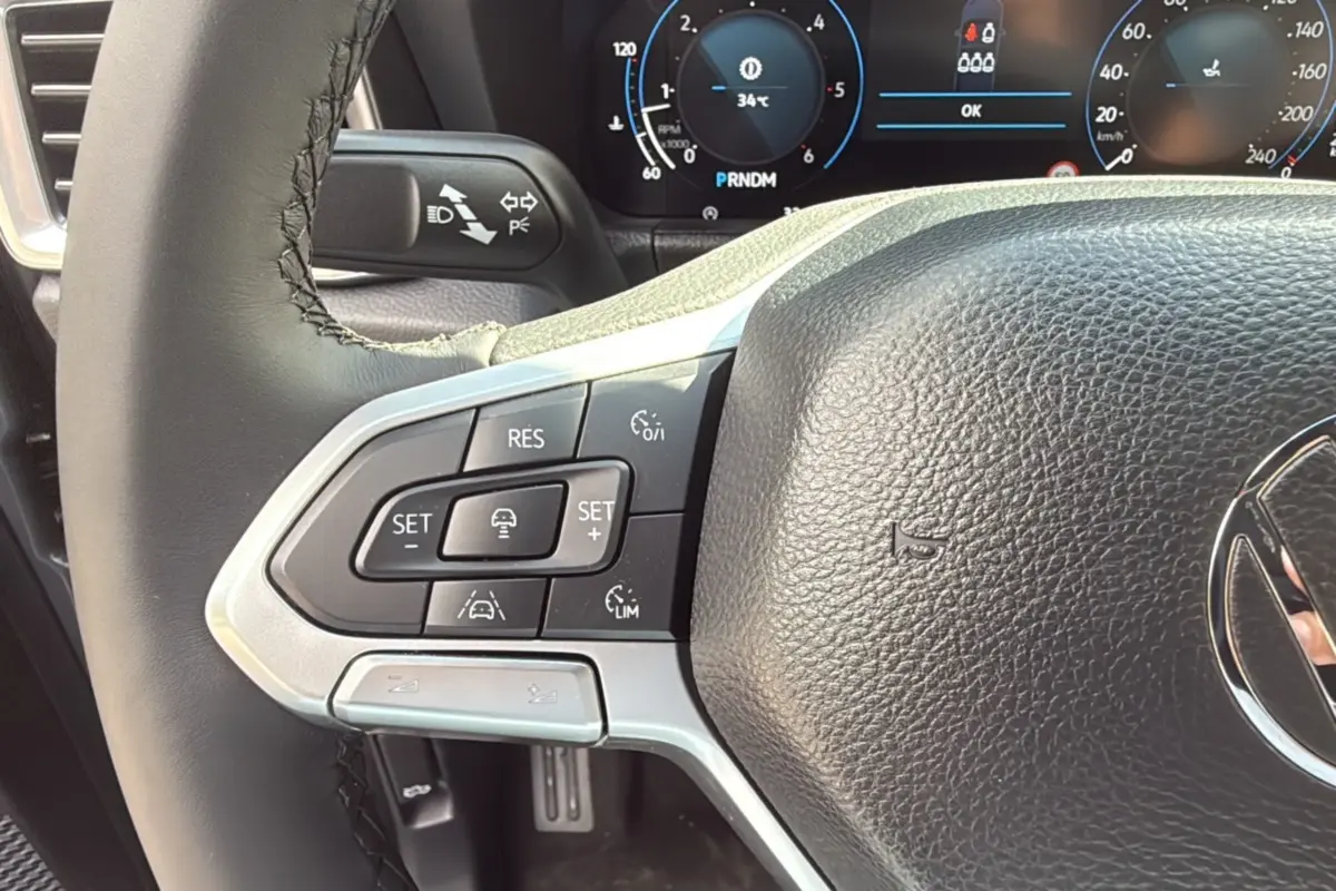Gros plan sur le volant cuir multifonctions du Volkswagen Amarok V6 240 BVA10 Aventura, avec commandes de régulateur.