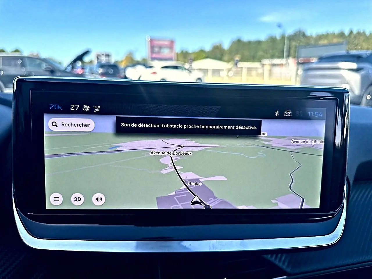 Écran tactile central du tableau de bord de la Peugeot 208 noire, affichant la navigation GPS en plein jour.