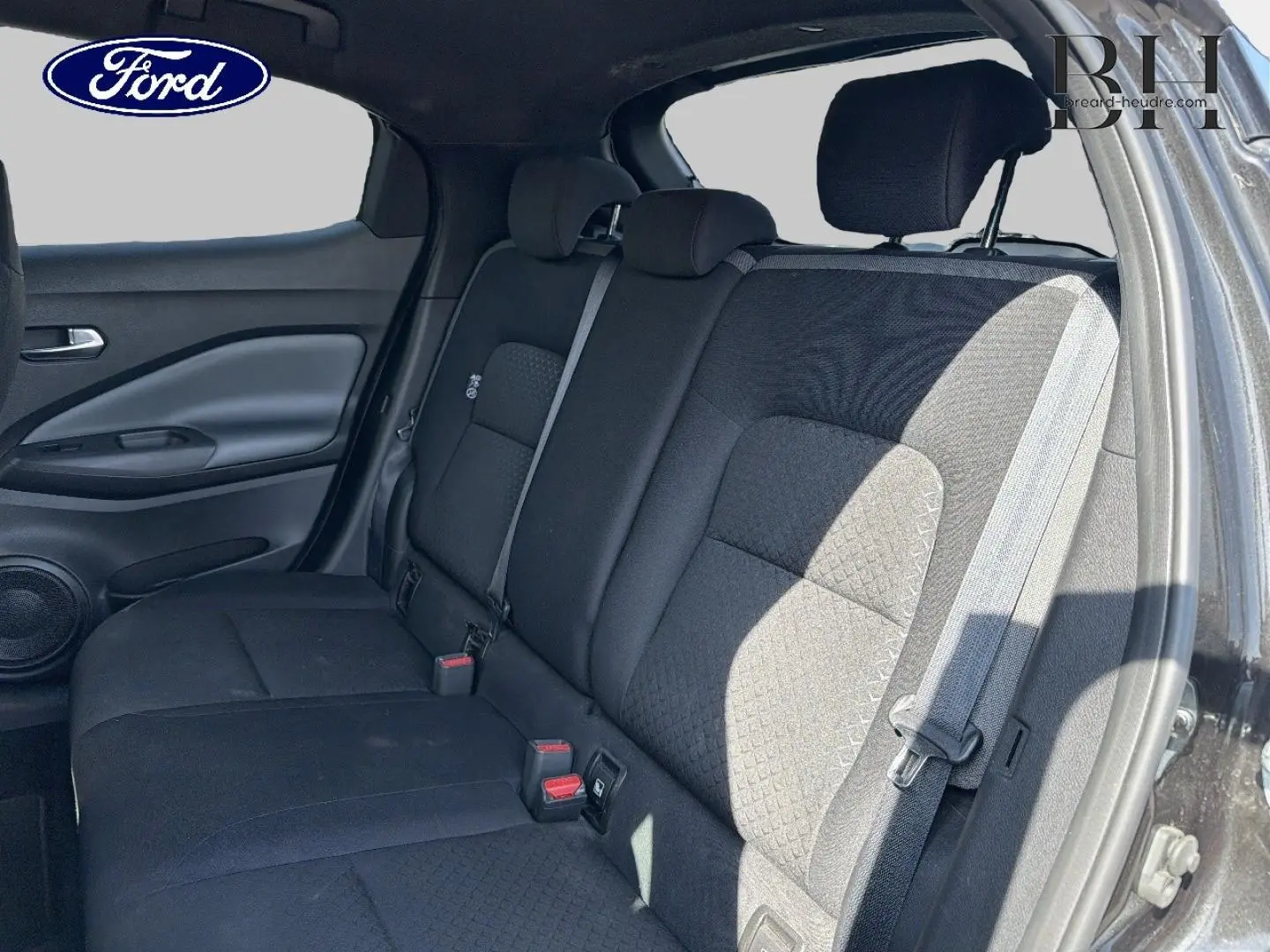 Vue intérieure sur la banquette arrière noire du Nissan Juke 2020, avec ceintures de sécurité et appuie-têtes visibles.