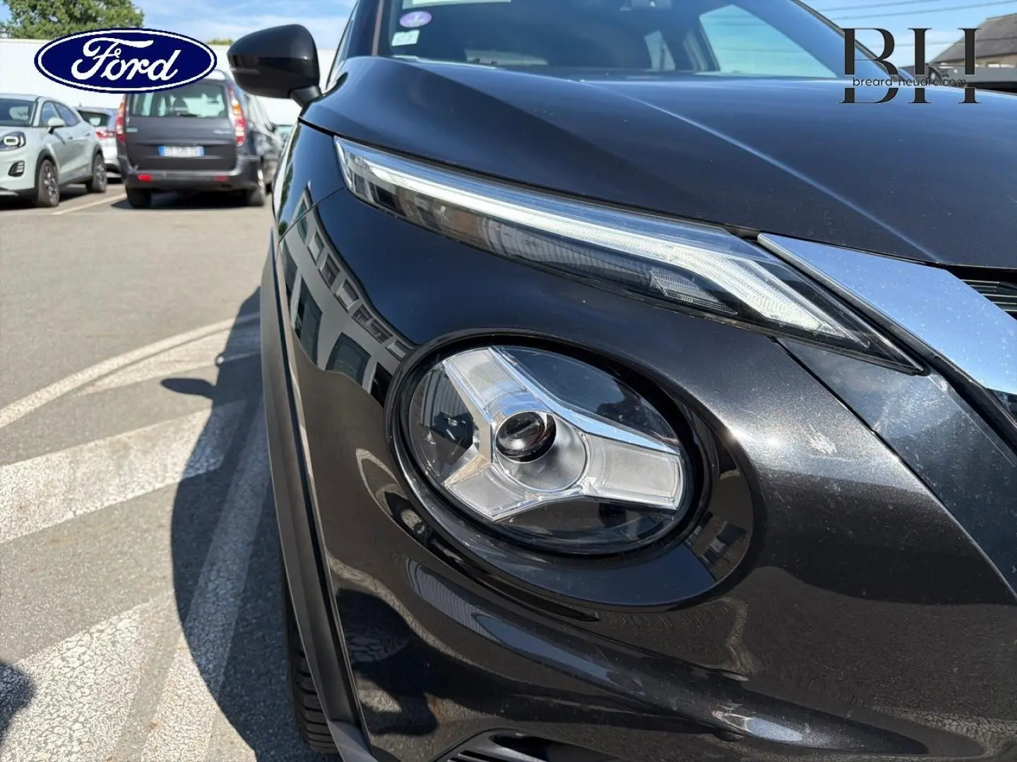 Gros plan sur le phare avant droit du Nissan Juke noir métallisé, soulignant son design moderne et ses lignes épurées.