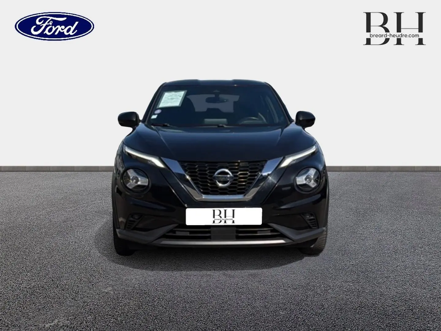 Vue frontale d'un Nissan Juke noir métallisé avec calandre en V chromée et phares ronds distinctifs.