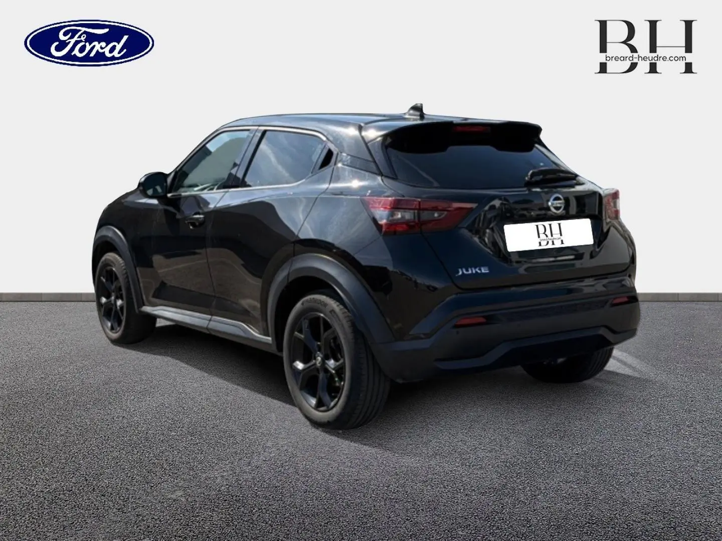 Vue 3/4 arrière droite du Nissan Juke noir métallisé avec jantes alu noires sur sol gris.