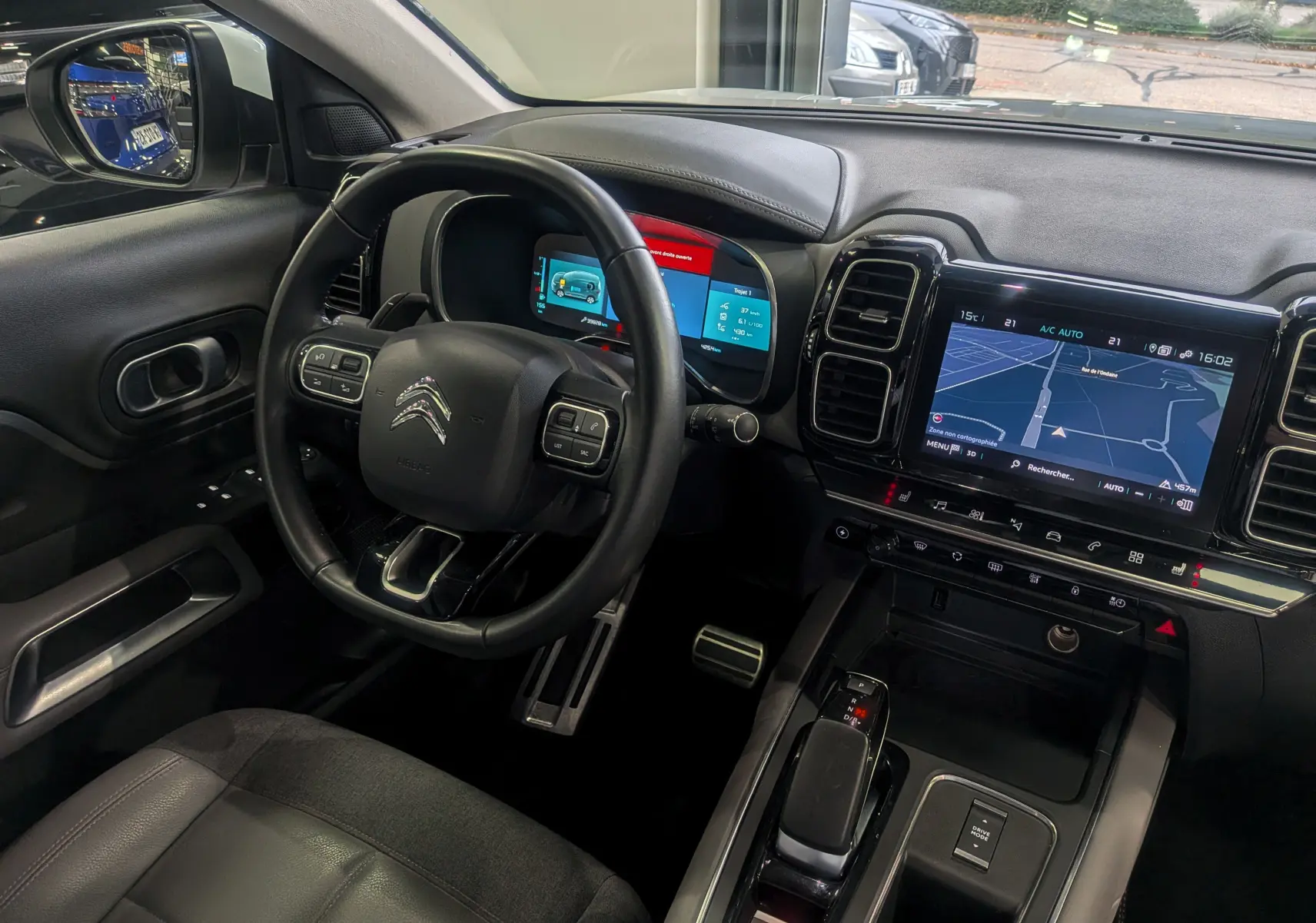 Intérieur noir du Citroën C5 Aircross hybride rechargeable 2021, vue du poste de conduite avec tableau de bord numérique et écran tactile GPS.