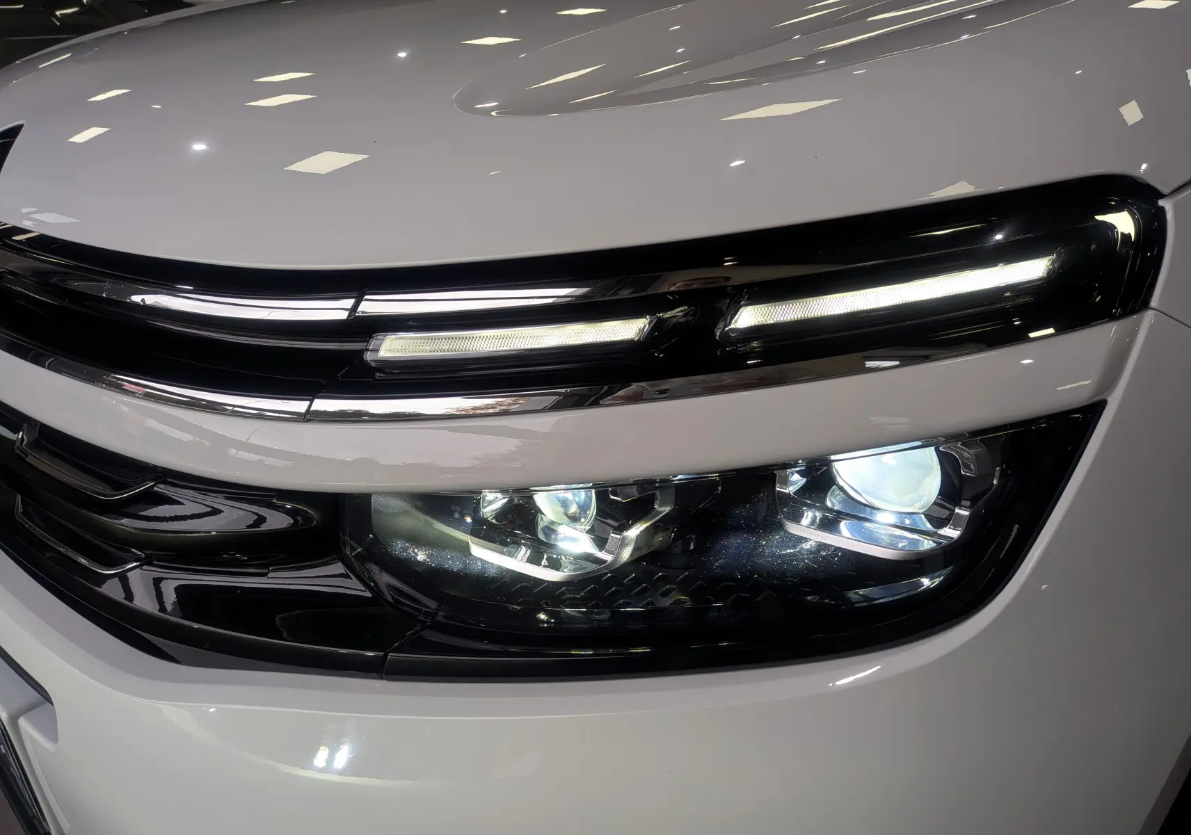 Gros plan sur le phare avant droit blanc glacier du Citroën C5 Aircross hybride rechargeable 2021 avec éclairage LED distinctif.