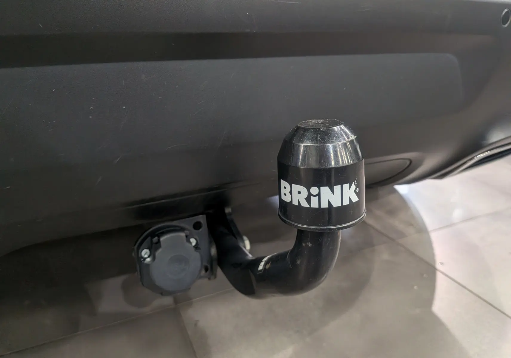 Gros plan sur l'attelage de remorque noir marqué BRINK sous le pare-chocs arrière du Citroën C5 Aircross blanc Glacier.