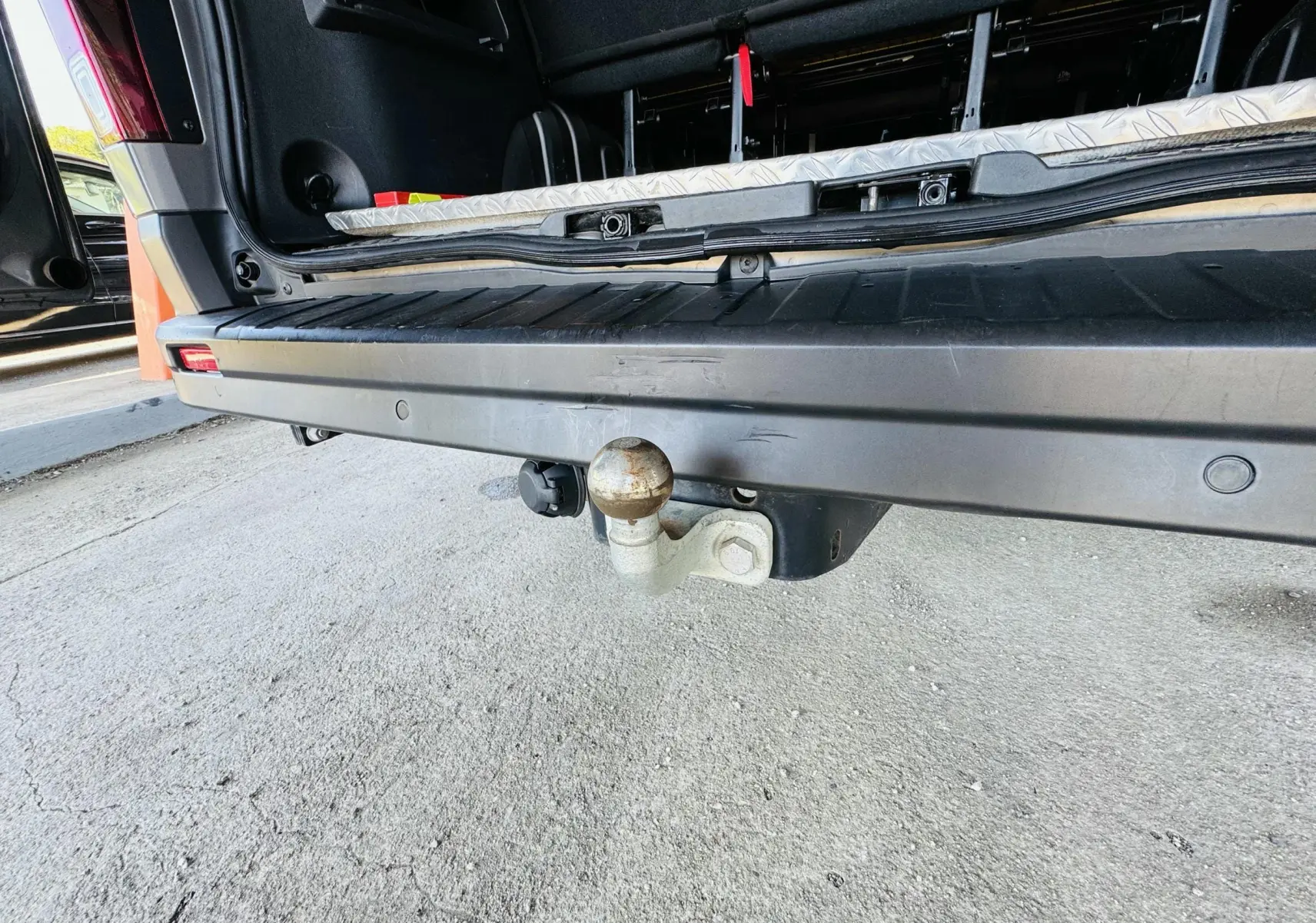 Gros plan sur l'attelage arrière gris du Nissan NV300 Combi avec porte ouverte et plancher visible.