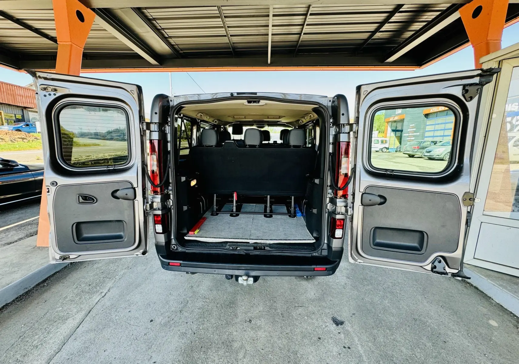 Vue arrière du Nissan NV300 Combi gris 2018 avec portes battantes ouvertes montrant l'intérieur et les sièges noirs.