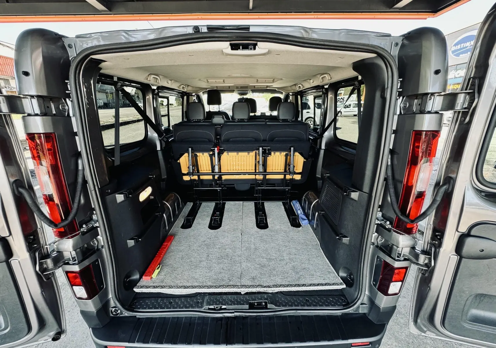 Vue arrière ouverte du Nissan NV300 Combi gris montrant l'espace intérieur et les sièges rabattus.