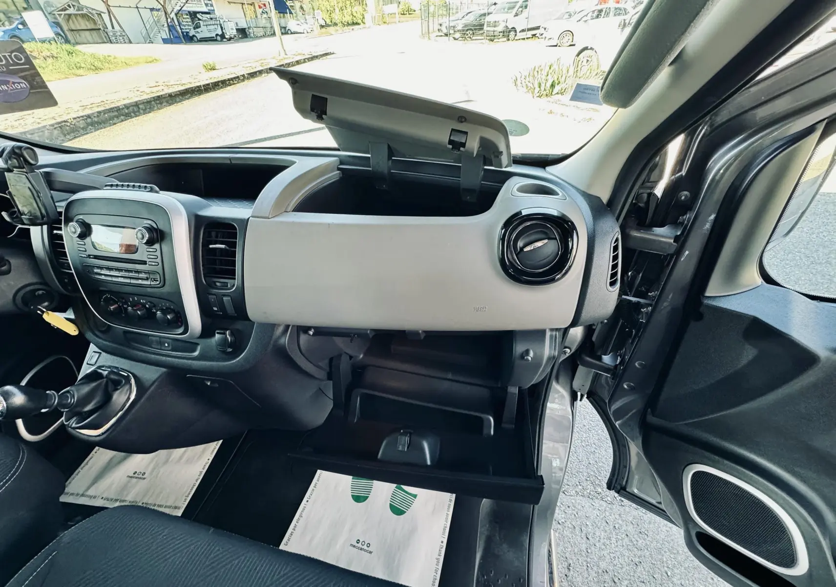 Vue intérieure côté passager du tableau de bord gris clair et noir avec boîte à gants ouverte d’un Nissan NV300 Combi gris de 2018.