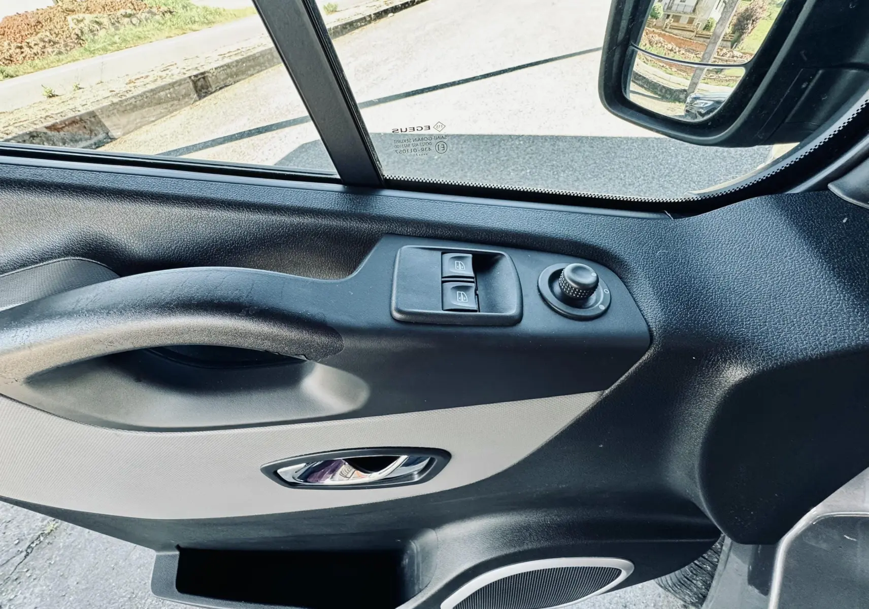 Vue intérieure côté conducteur de la porte gris clair et noir du Nissan NV300 Combi avec commandes de vitres et rétroviseur.