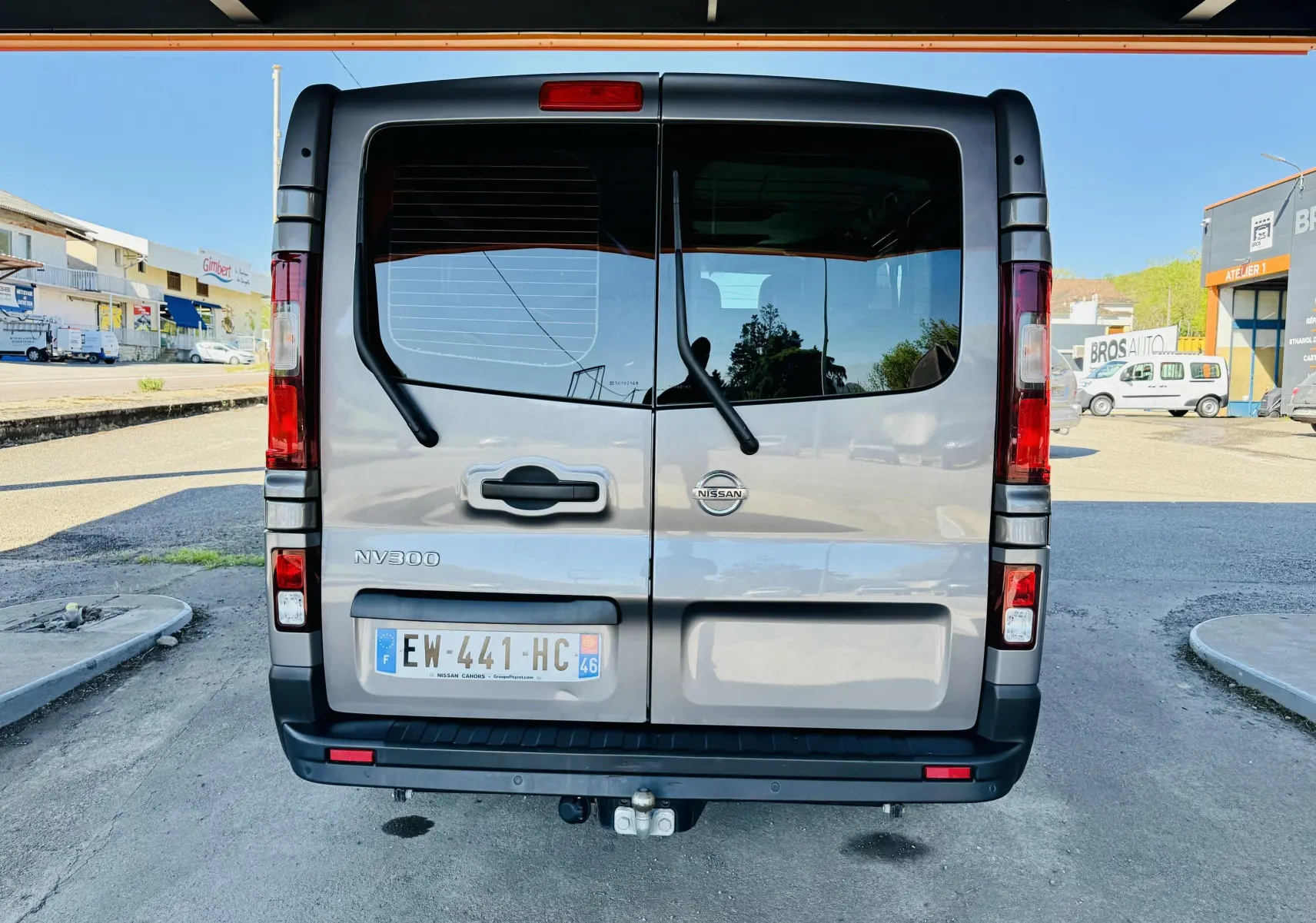 Vue arrière d’un Nissan NV300 Combi gris avec portes battantes et plaque d’immatriculation française visible.