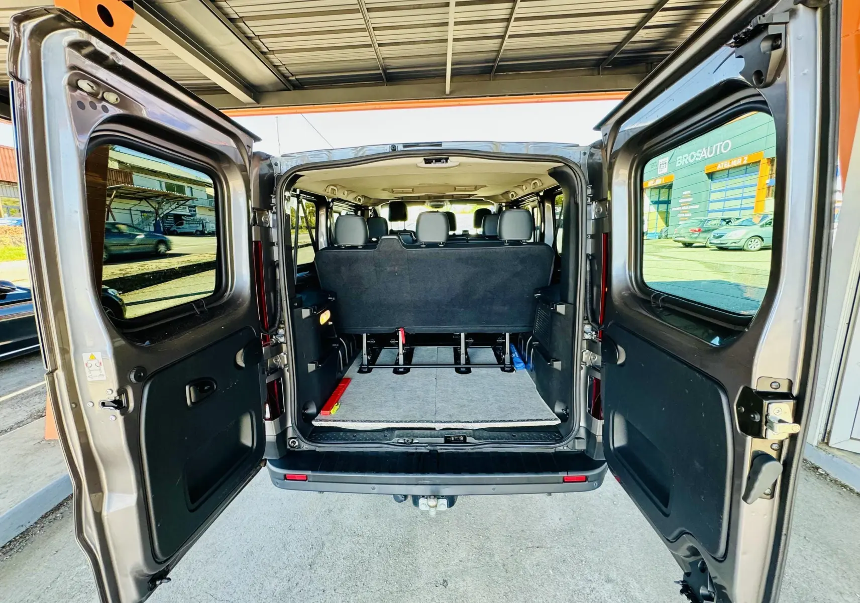 Vue arrière du Nissan NV300 Combi gris avec portes ouvertes montrant l'espace intérieur et les sièges arrière.