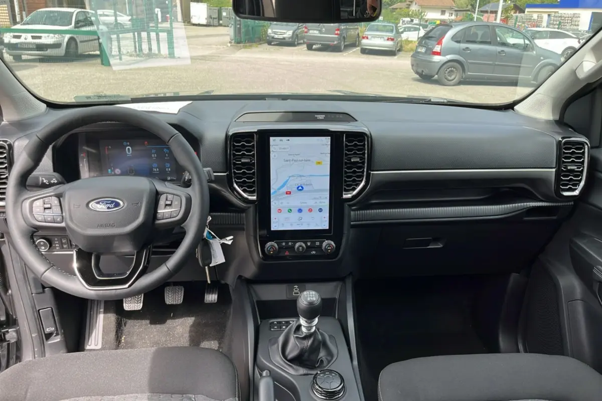 Vue intérieure frontale du Ford Ranger gris carbone 2025, avec volant multifonctions et écran tactile vertical.