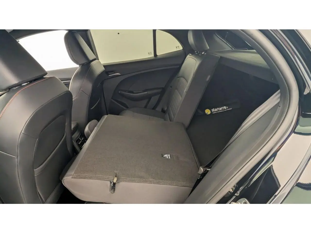 Vue intérieure arrière droite du MG3 1.5 Hybrid+ 195 Luxury, montrant la banquette rabattue et la sellerie tissu/similicuir noir.