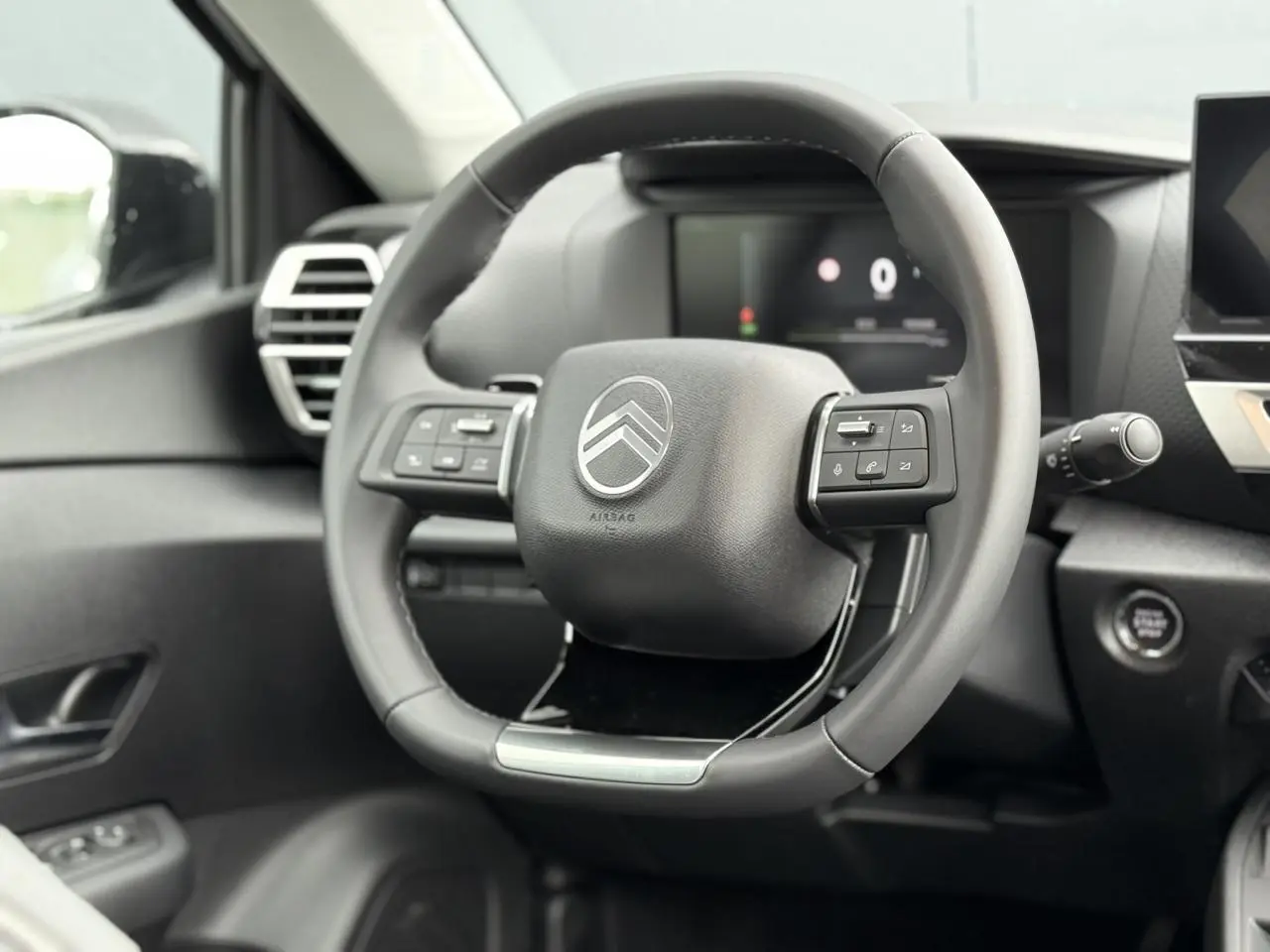 Volant cuir noir avec commandes intégrées et logo Citroën, vue rapprochée de l'habitacle avant du C4 hybride 2025.