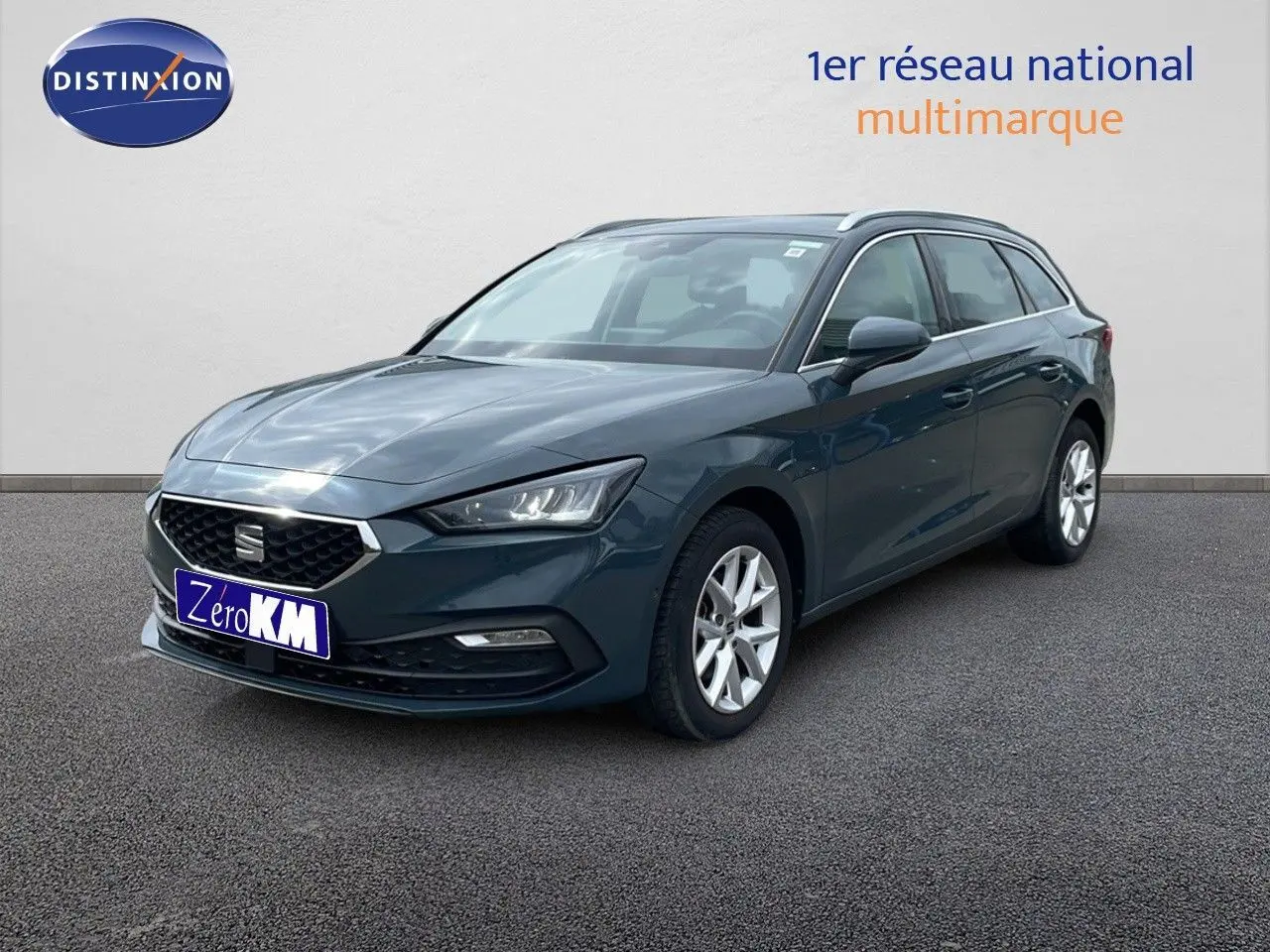 SEAT LEON ST gris magnétique métal vue 3/4 avant droit sur sol bitumé devant un mur clair.