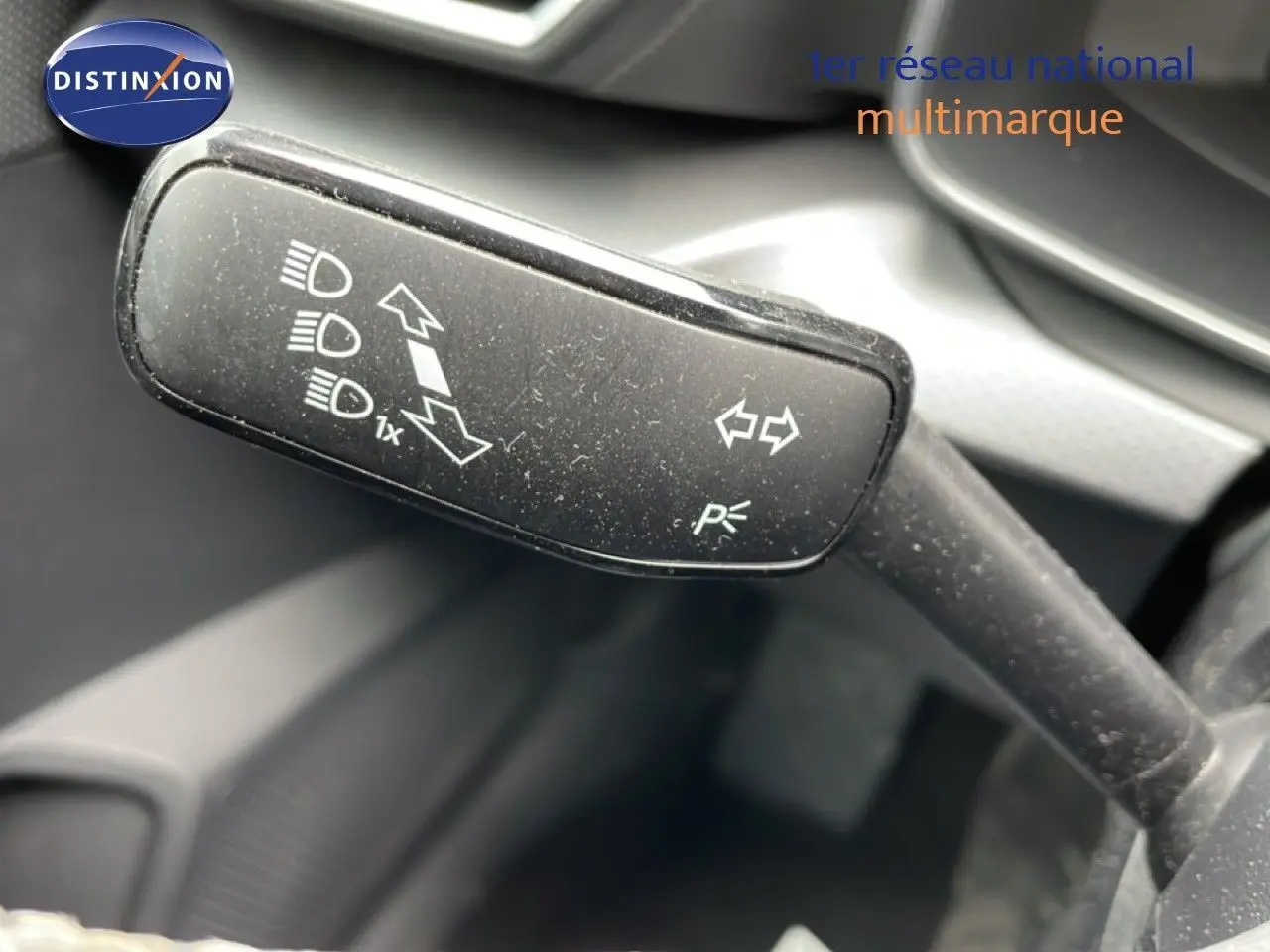 Gros plan sur la manette de clignotants noire à l'intérieur d'une SEAT LEON ST gris magnétique, avec pictogrammes blancs visibles.