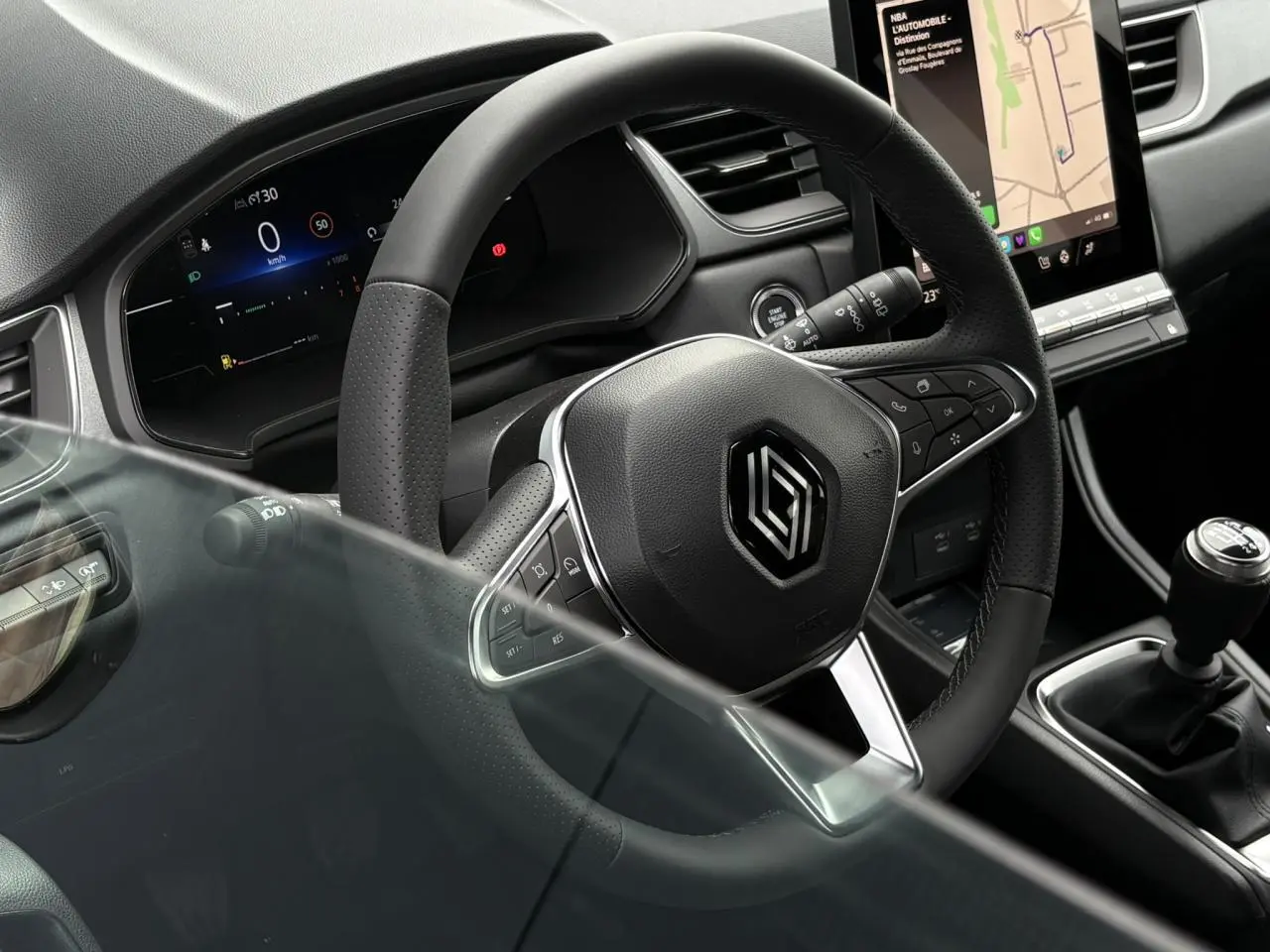 Vue rapprochée du volant noir perforé et du levier de vitesses manuel du Renault Captur 2025 avec écran tactile vertical.