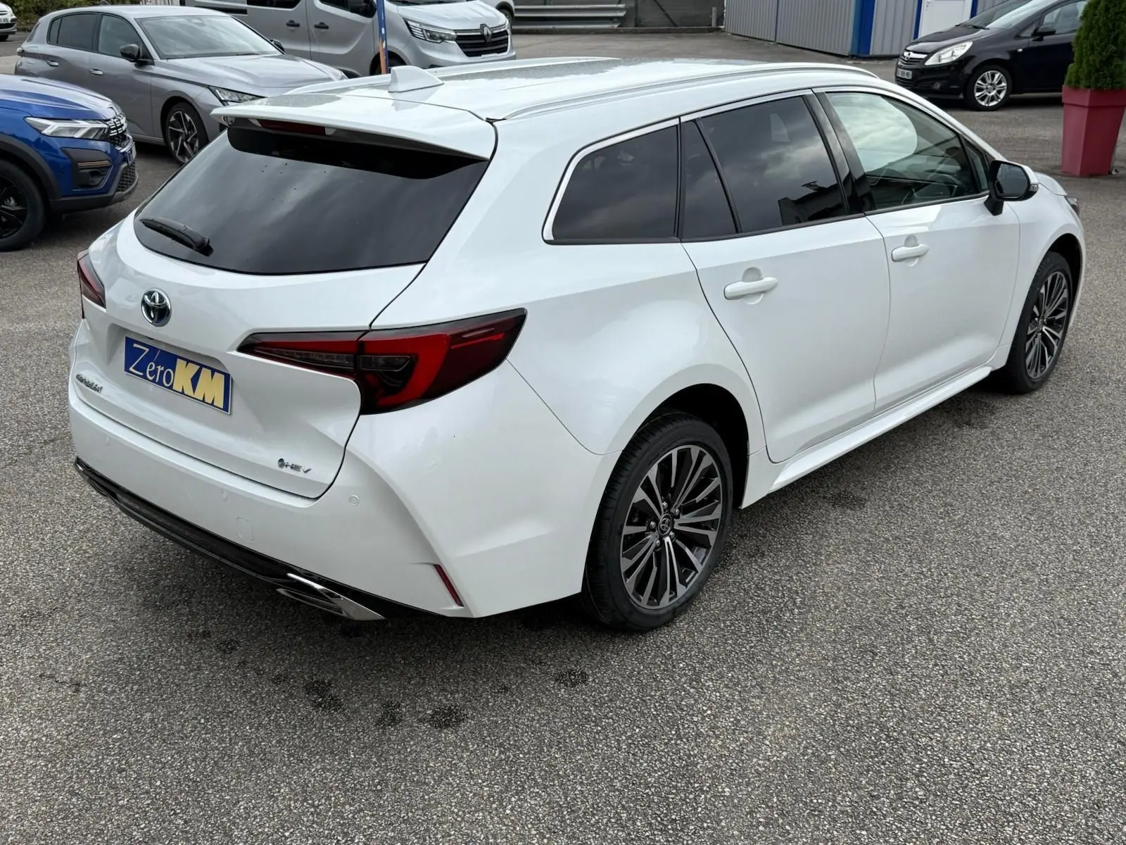 Toyota Corolla Touring Sport blanc lunaire nacré vue 3/4 arrière droit avec jantes alliage et vitres teintées.