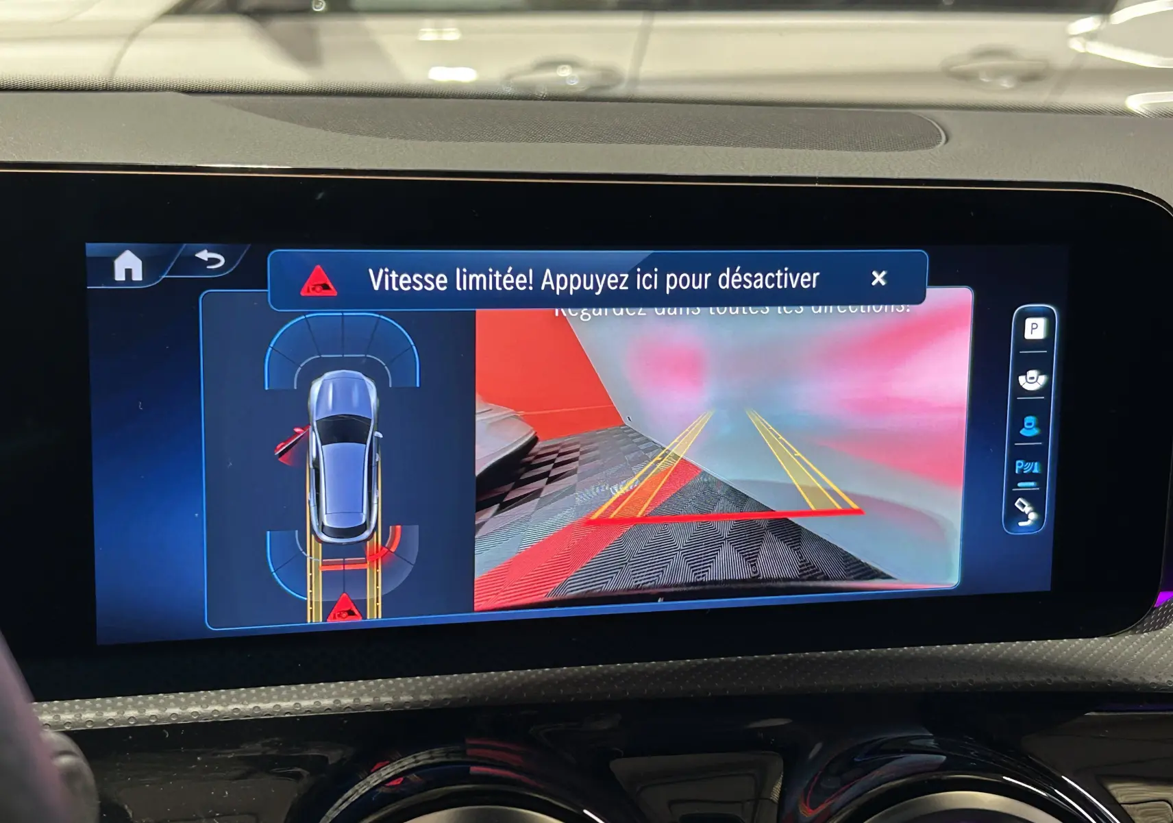 Écran central montrant la caméra de recul et l'alerte de vitesse limitée dans une Mercedes CLA Shooting Brake noire.