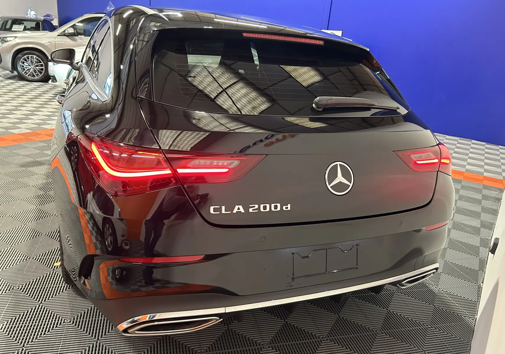 Vue 3/4 arrière d'une Mercedes CLA 200d noire métallisée avec feux LED et double sortie d'échappement chromée.