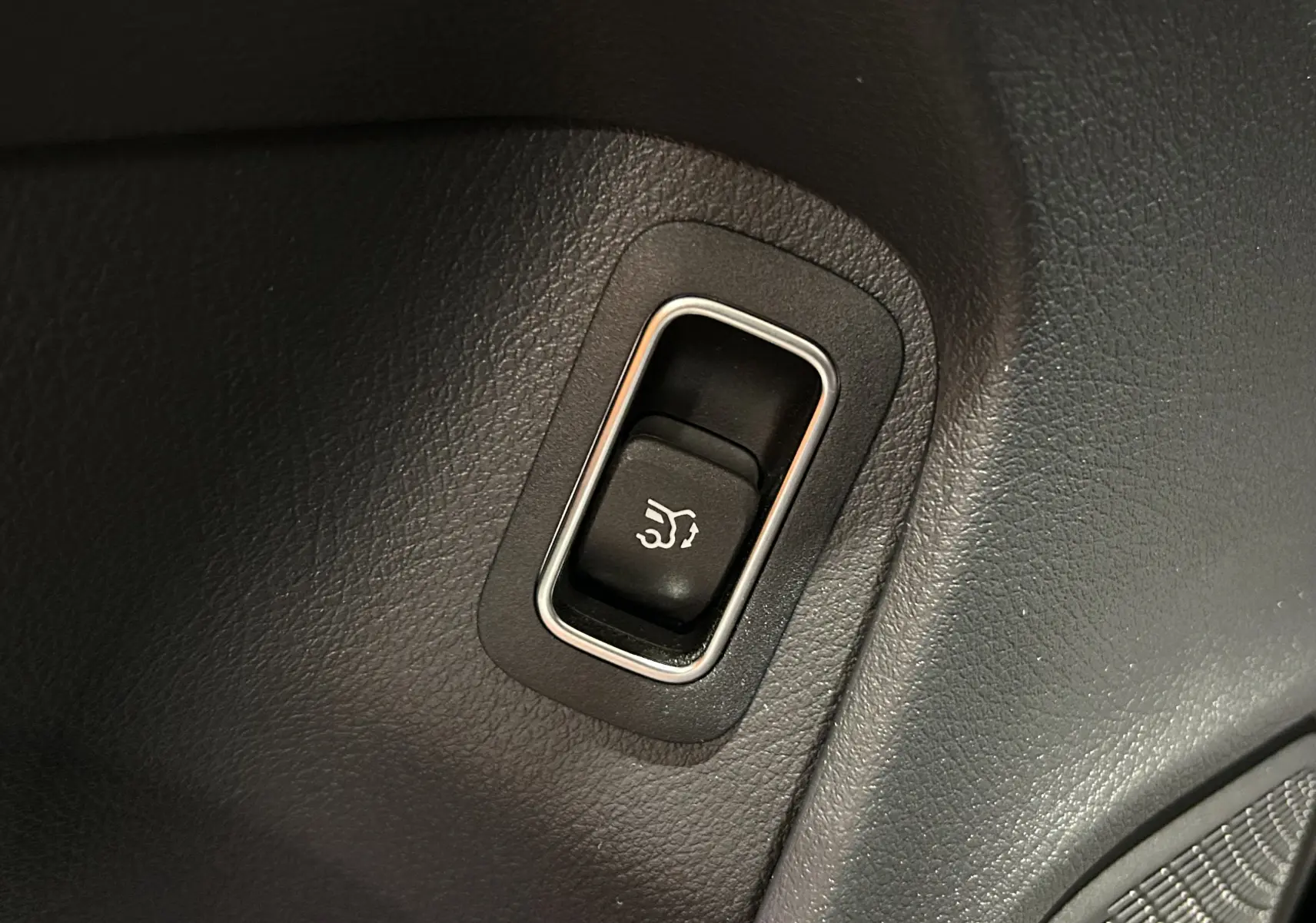 Bouton noir avec symbole d'ouverture du hayon, intégré dans le panneau intérieur noir d'une Mercedes CLA Shooting Brake 2024.