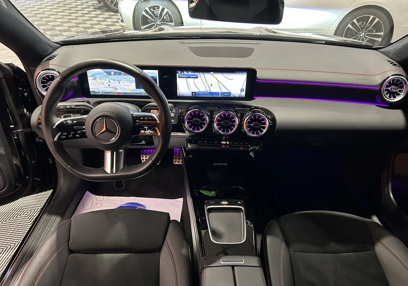 Intérieur noir de la Mercedes CLA Shooting Brake II 200D AMG, vue de face sur le tableau de bord avec éclairage violet et écran large.