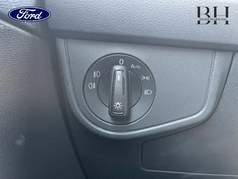 Sélecteur de phares noir sur tableau de bord gris foncé d'une Volkswagen Polo Reflet d'Argent métallisé, vue rapprochée côté conducteur.