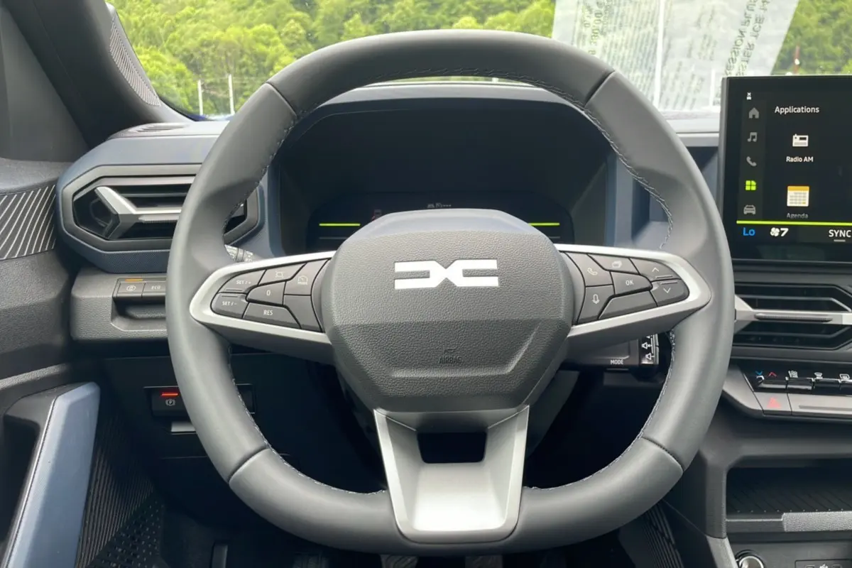 Vue rapprochée du volant cuir noir du Dacia Bigster 2025, avec commandes intégrées et écran tactile central visible.