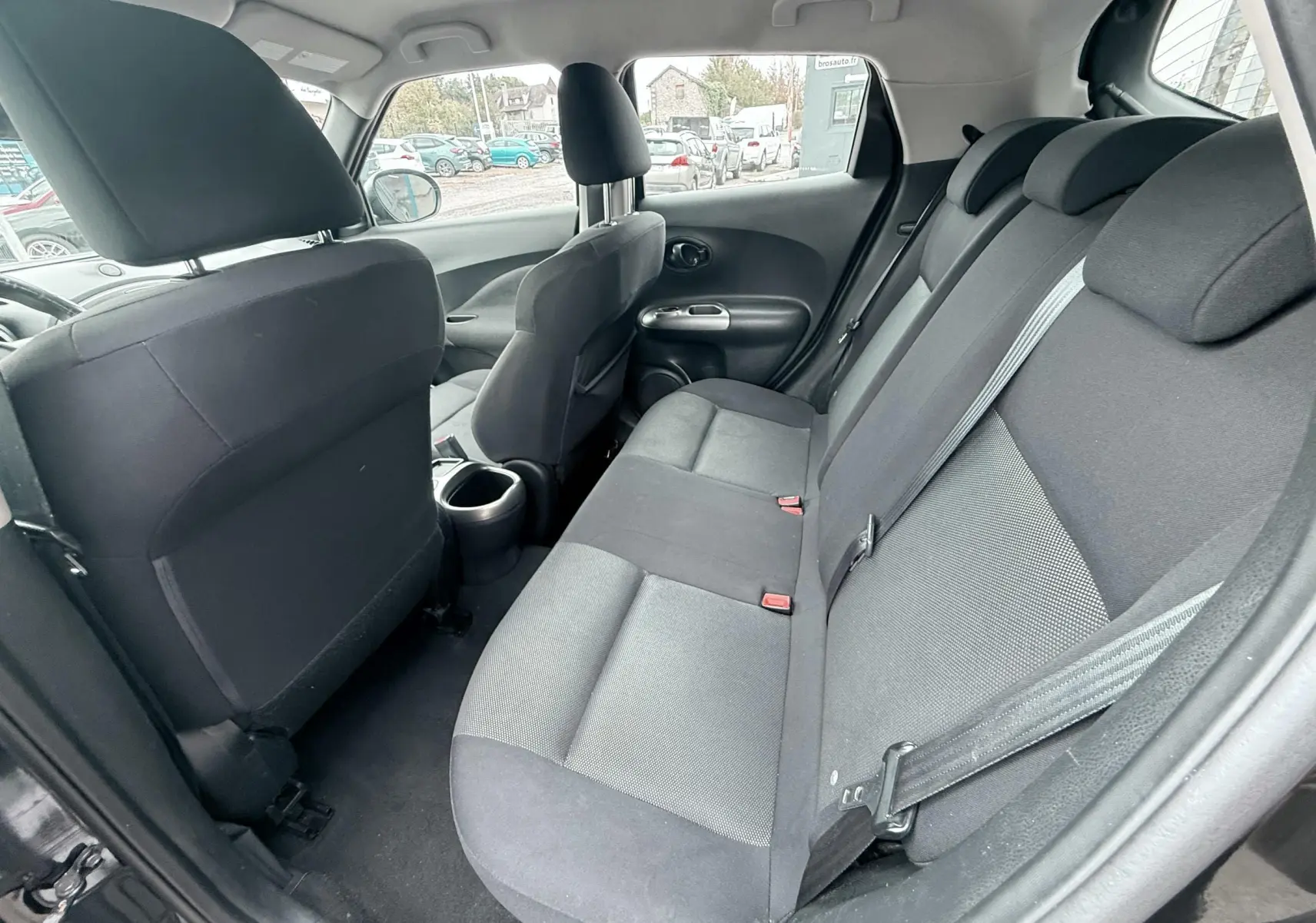 Vue intérieure arrière droite du Nissan Juke noir de 2012, montrant les sièges arrière en tissu noir et gris.