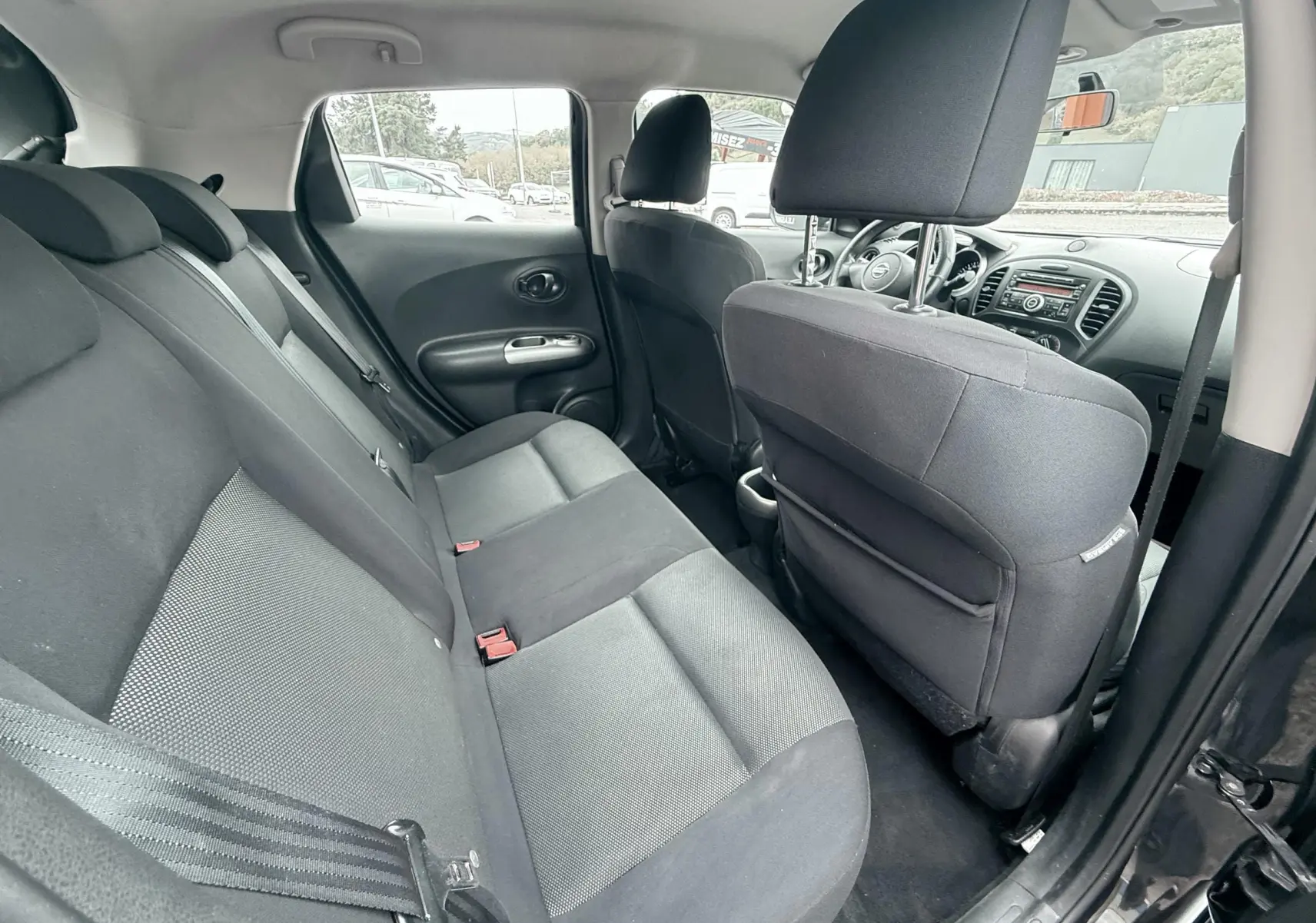 Vue intérieure côté gauche montrant la banquette arrière noire et les sièges avant du Nissan Juke 2012.