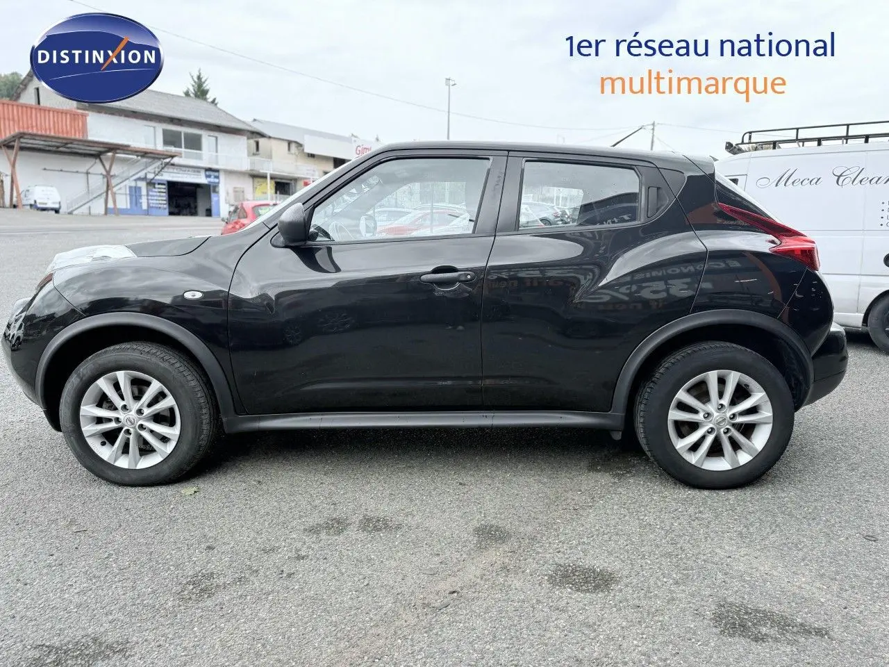 Profil côté gauche d'un Nissan Juke noir de 2012, compact et urbain, garé sur un parking extérieur.