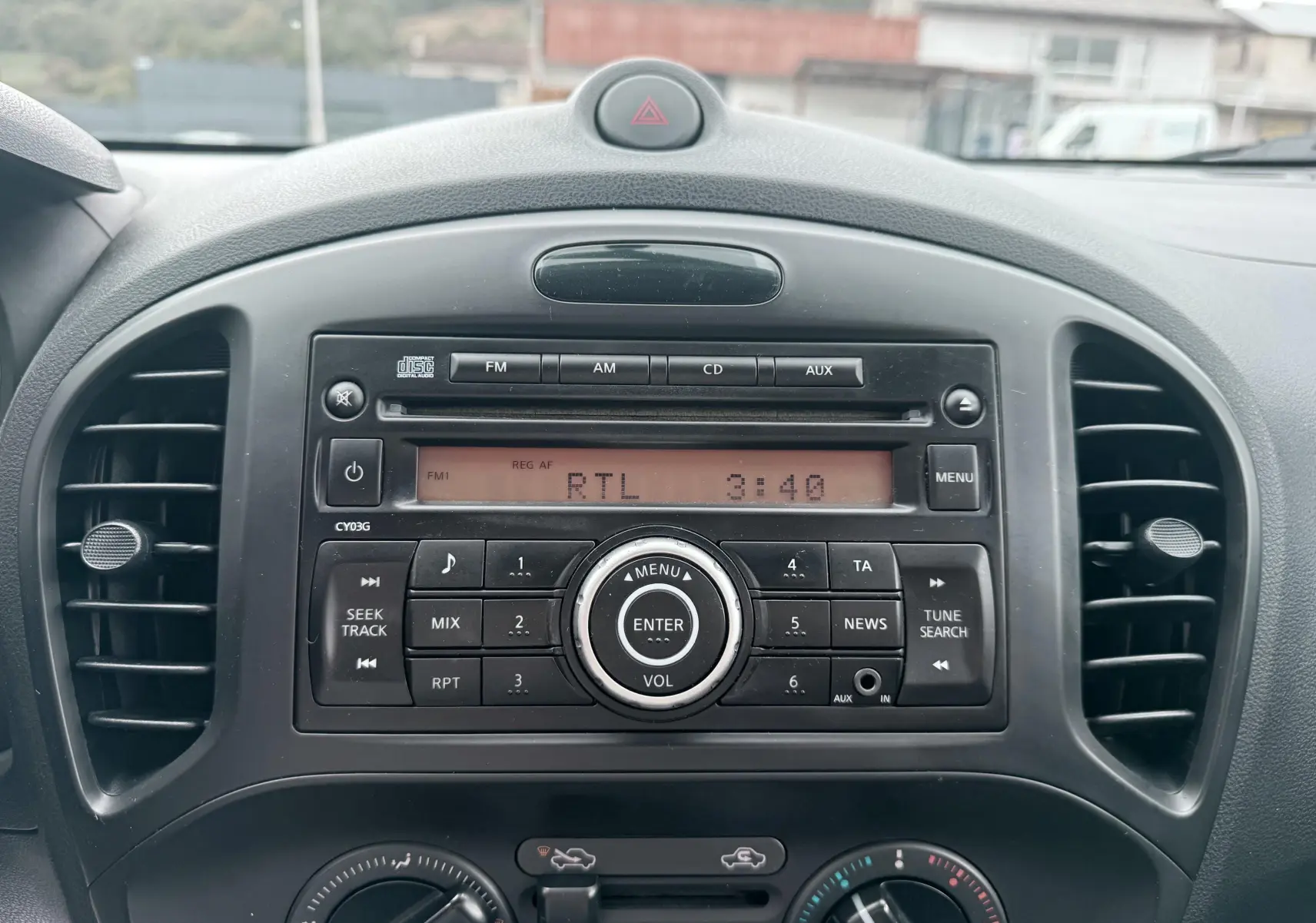 Vue rapprochée de la radio et des commandes de climatisation noires du tableau de bord d’un Nissan Juke 2012.