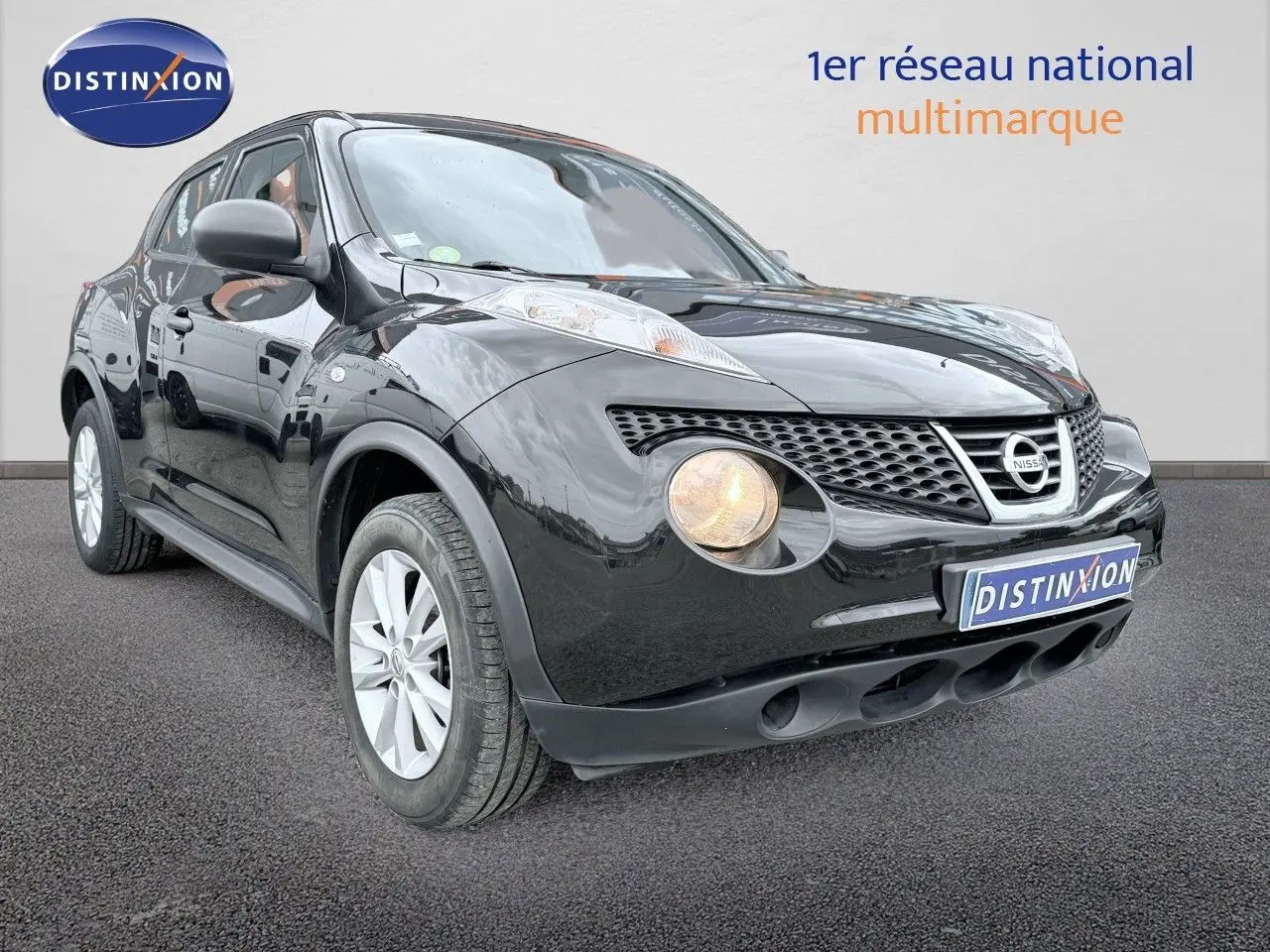 Nissan Juke noir en 3/4 avant droit avec phare avant allumé sur fond neutre.