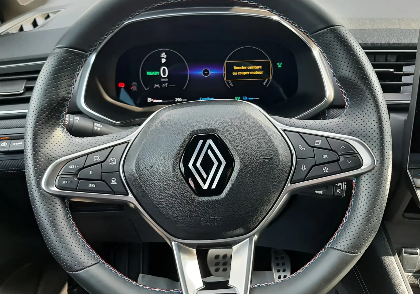 Volant en cuir perforé avec logo Renault au centre et tableau de bord numérique allumé dans un Renault Captur 2024.