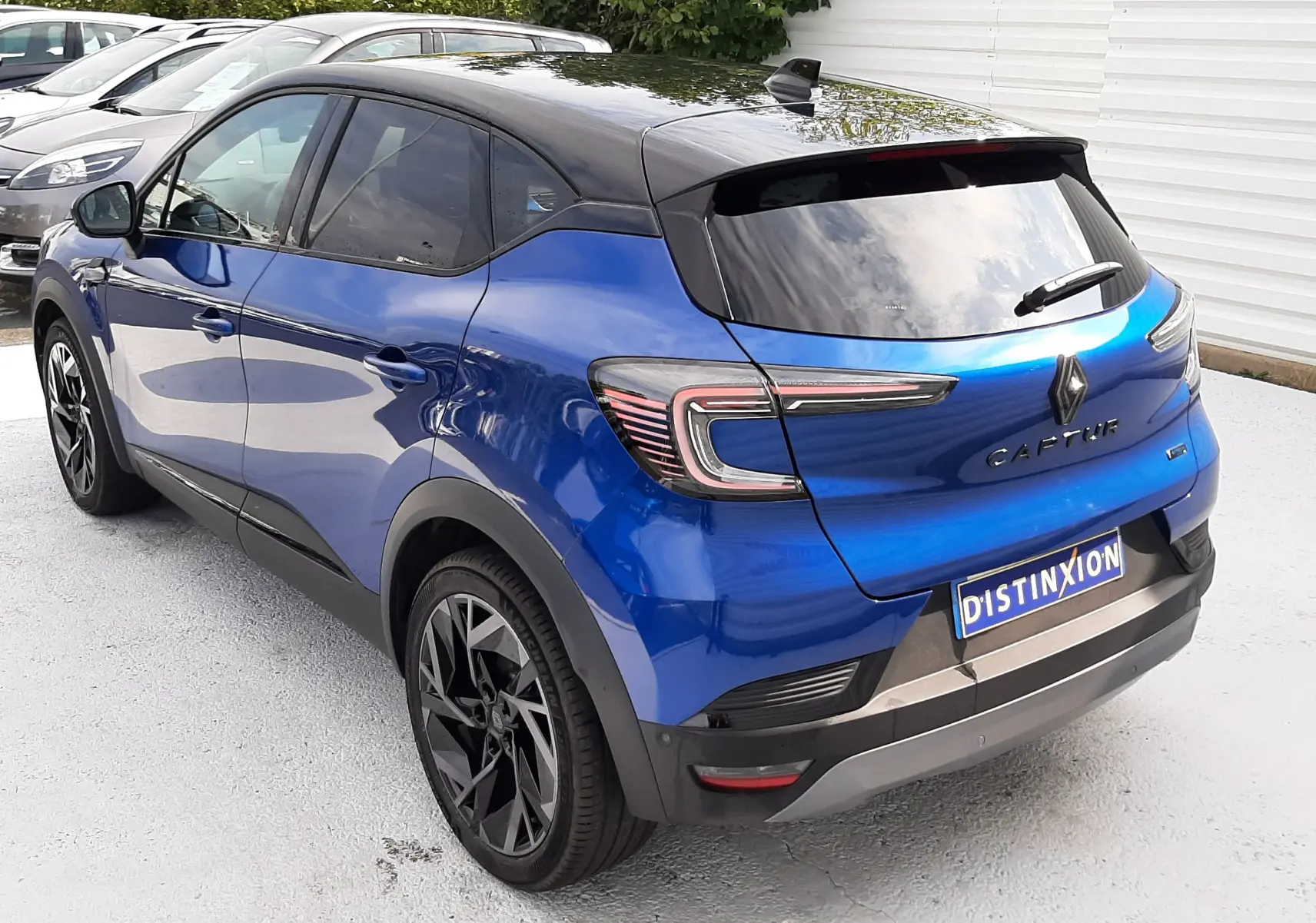 Vue 3/4 arrière droite du Renault Captur 2024 bleu Iron avec toit noir et jantes noires distinctives.