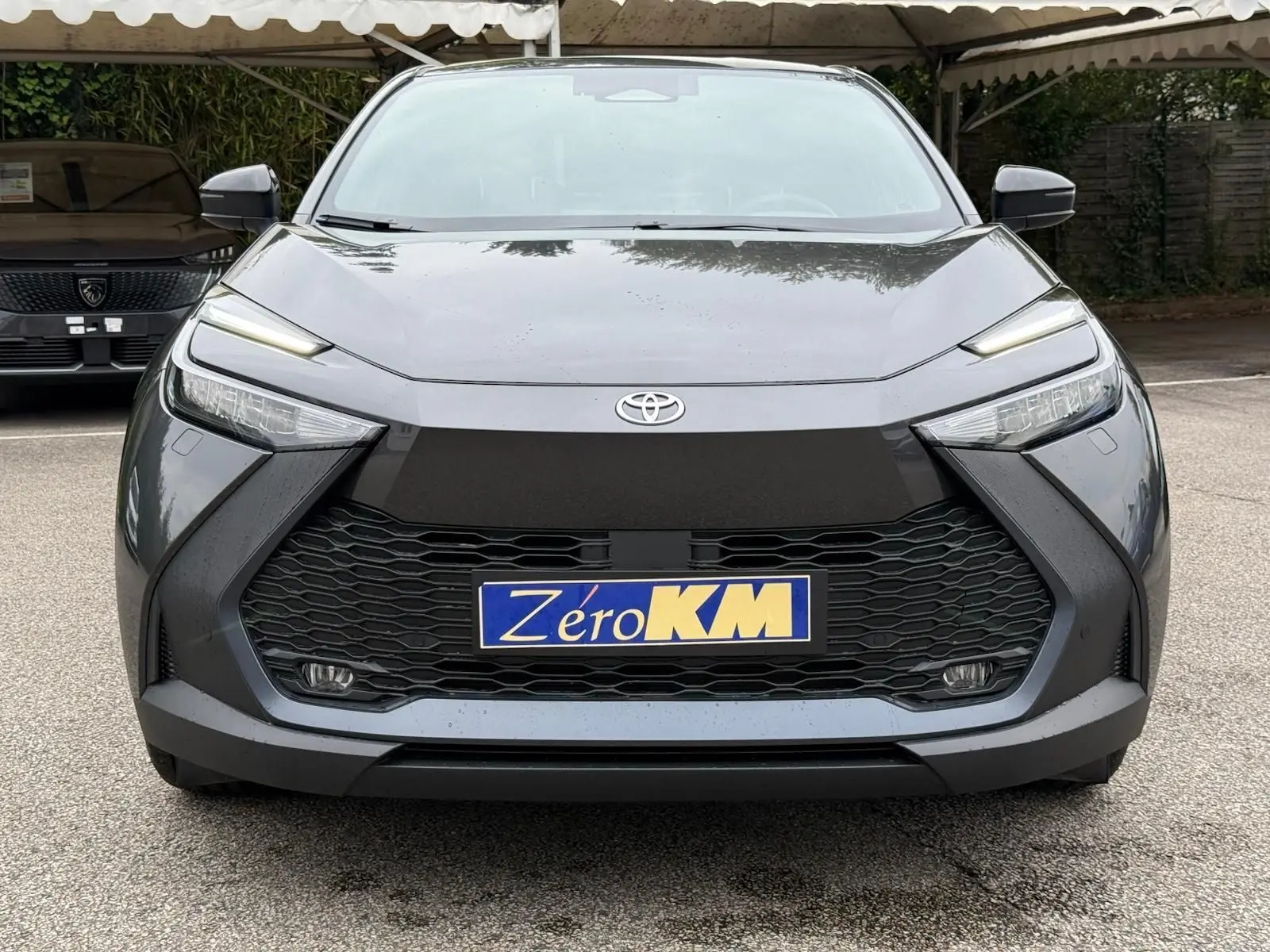 Vue frontale du Toyota C-HR 1.8 140CH STYLE gris atlas avec calandre noire et phares LED fins.