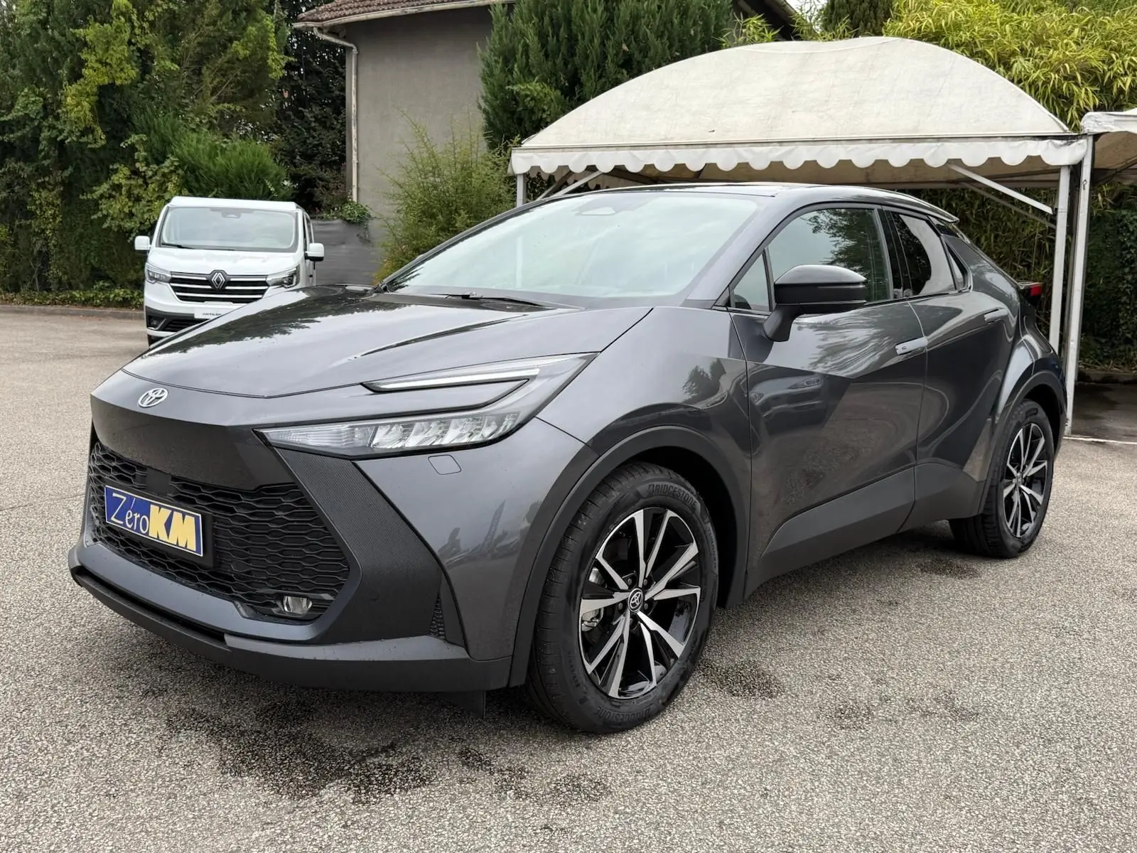 Toyota C-HR 1.8 140CH STYLE gris atlas vu en 3/4 avant droit avec jantes noires et détails noirs contrastants.