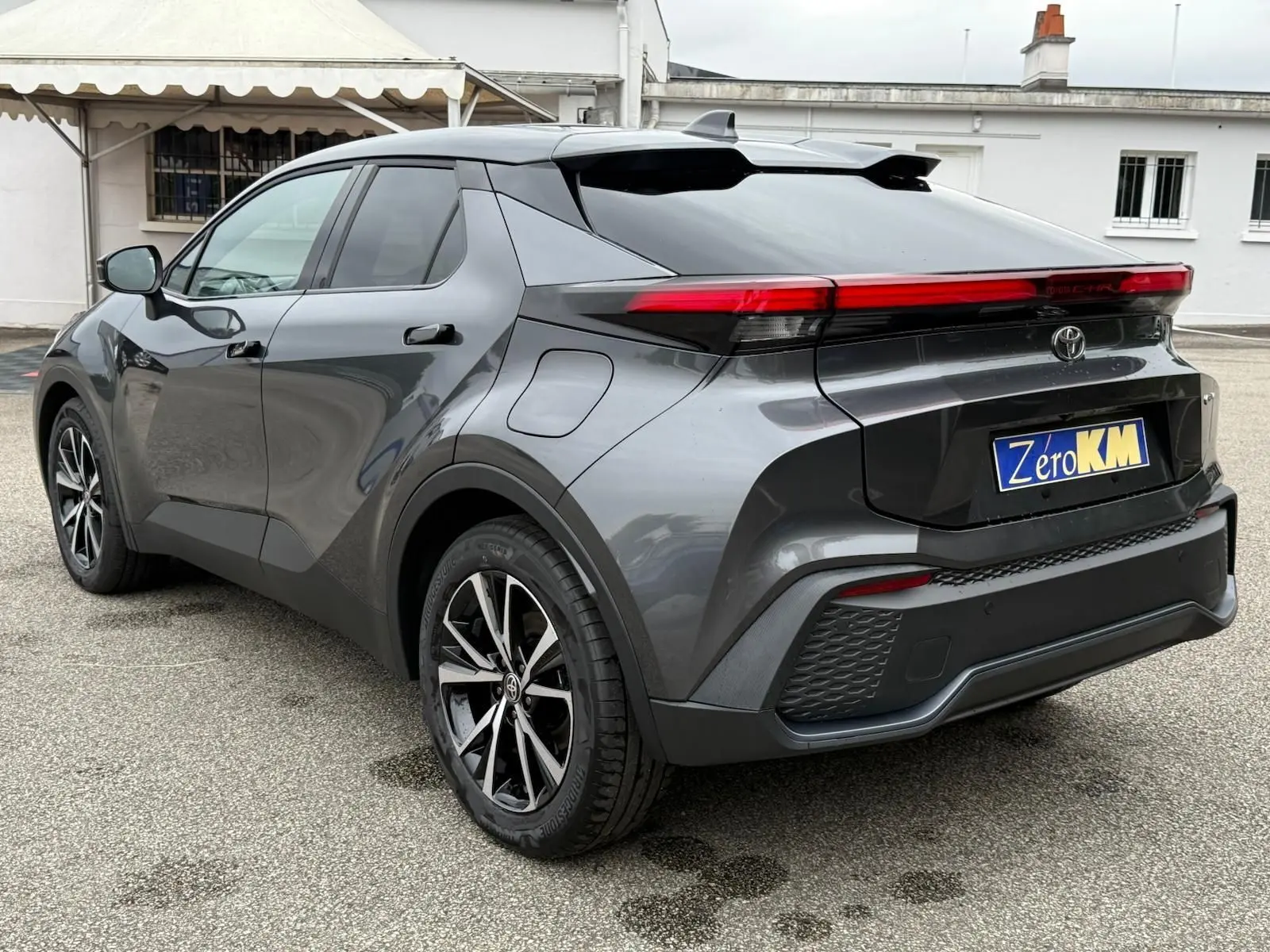 Toyota C-HR 1.8 140CH STYLE gris atlas vu en 3/4 arrière droit, avec feux arrière LED et jantes alliage noires.
