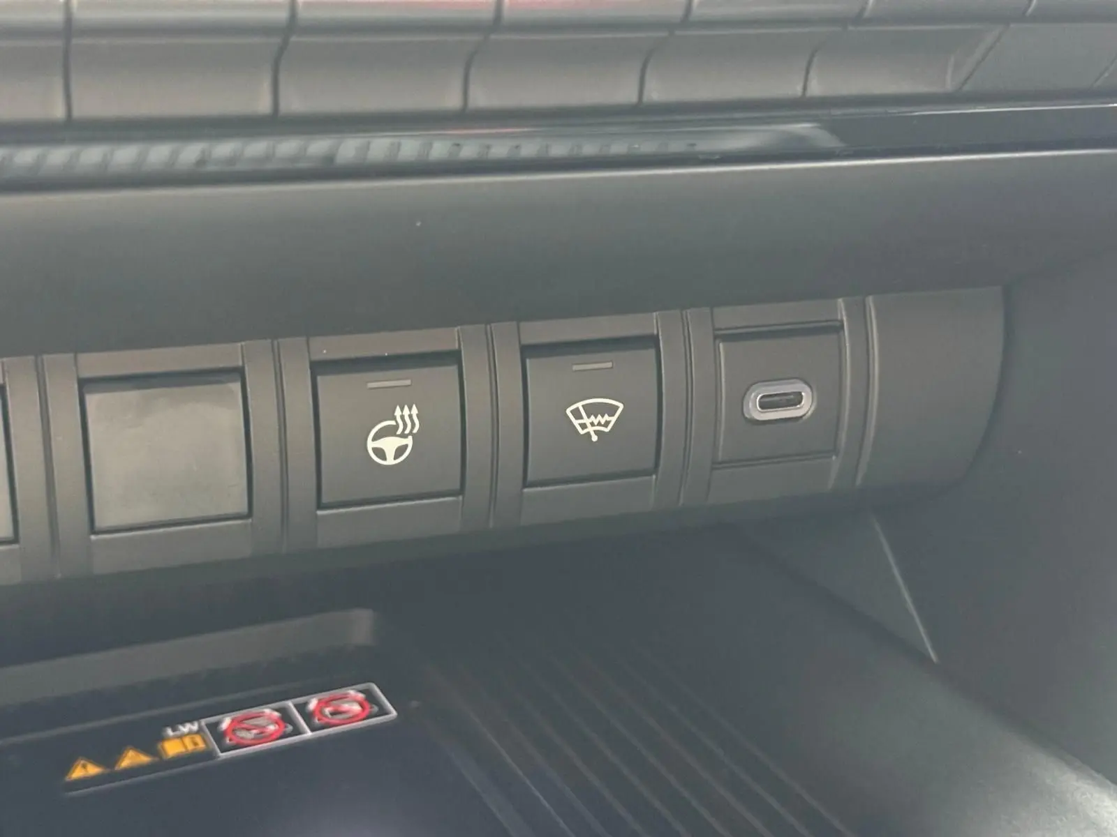 Gros plan sur les commandes du tableau de bord du Toyota C-HR gris atlas, avec bouton de volant chauffant et dégivrage.