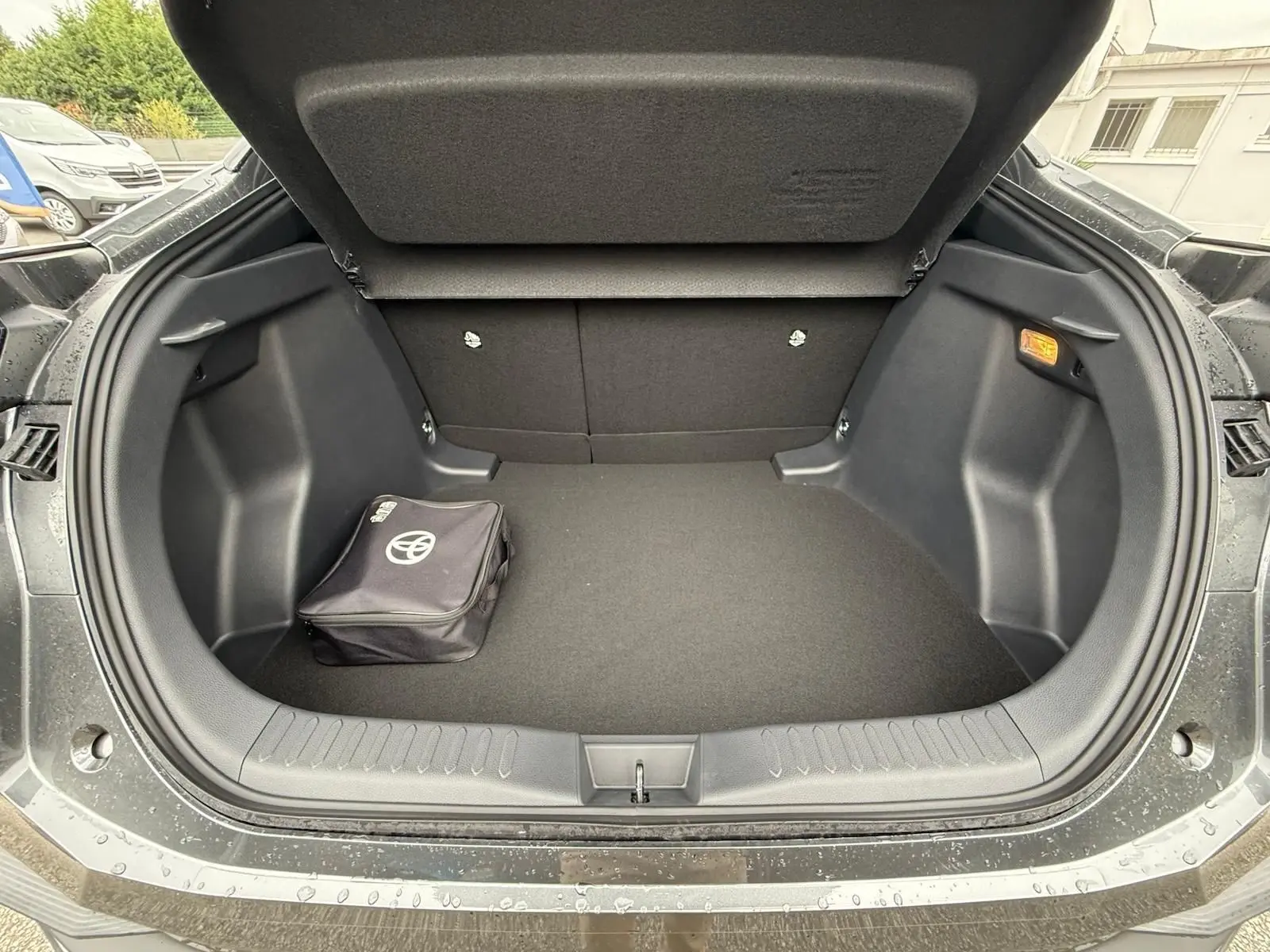 Coffre ouvert du Toyota C-HR gris atlas 2025 montrant un sac de secours noir avec logo Toyota.