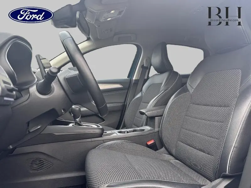 Intérieur avant côté conducteur d'une Renault Arkana bleu Zanzibar, sièges tissu noir Titane avec accoudoir central.